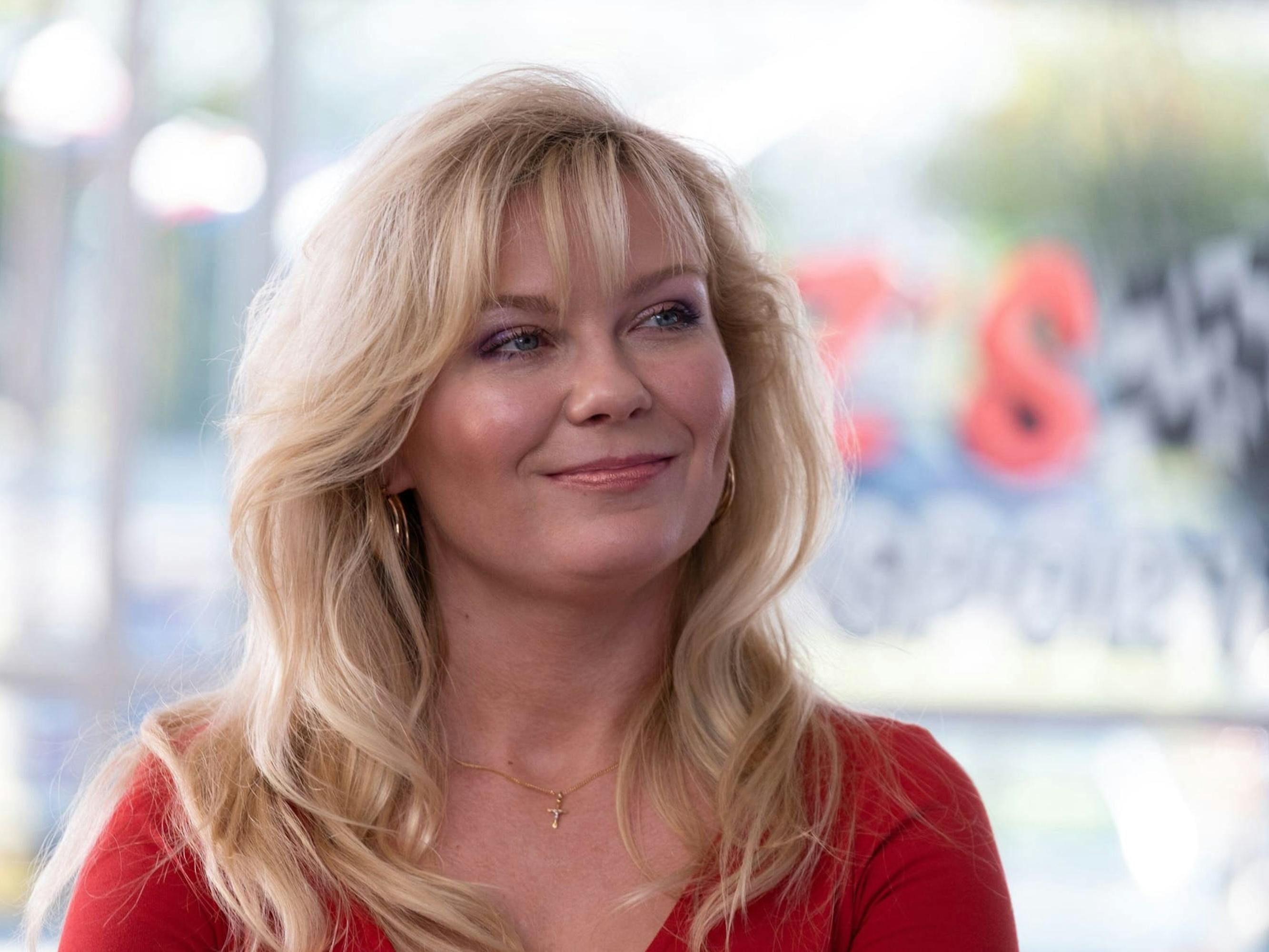 Krystal Stubbs (Kirsten Dunst) wears a red shirt and smiles.