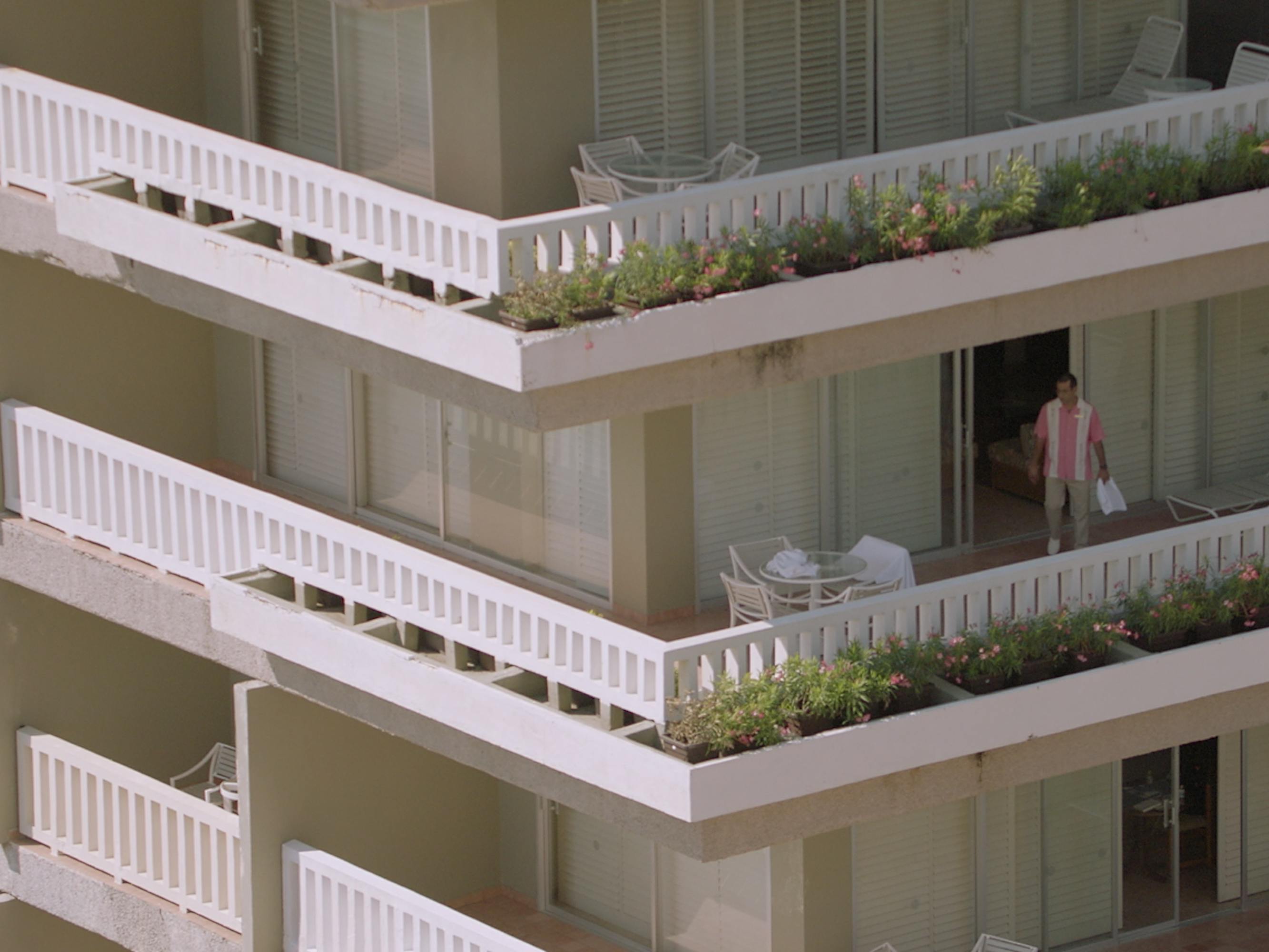 The hotel from Tiempo compartido is white and has many layers. A few of the balconies picture have gardens and outdoor chairs.