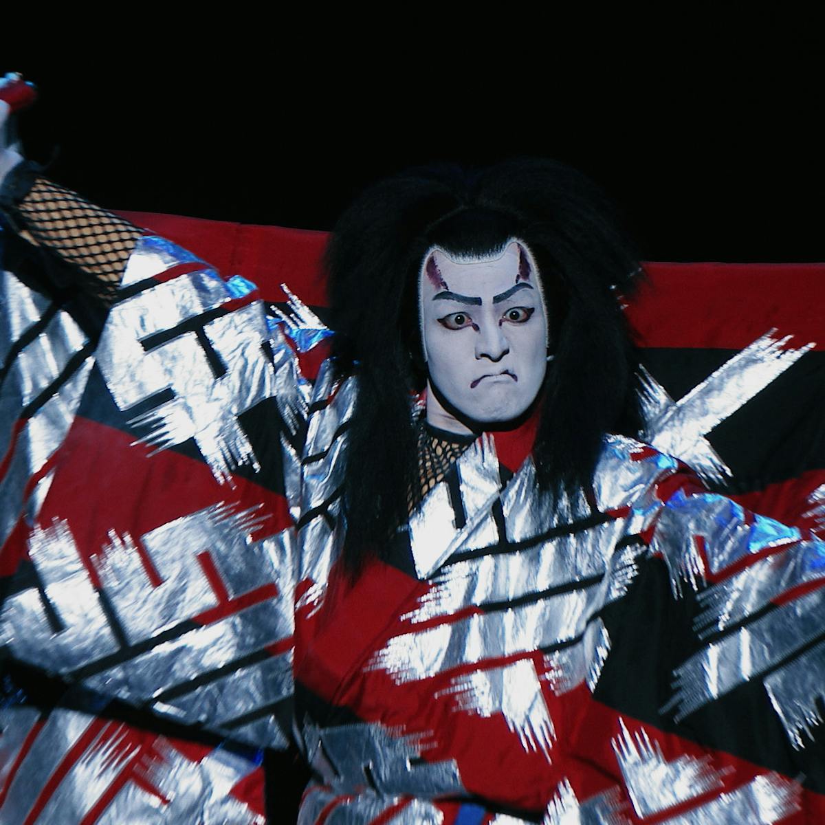 An actor does Kabuki in a white, black, and red robe.
