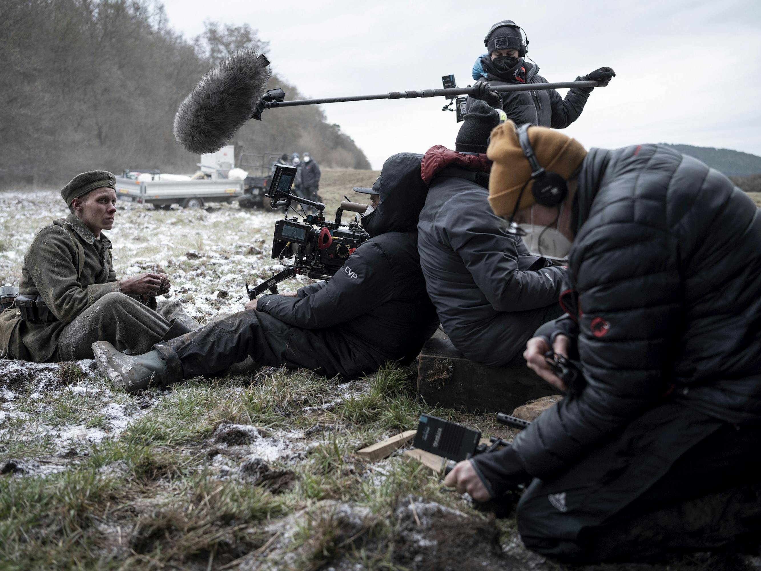 Felix Kammerer and crew behind the scenes. Felix sits on frosty ground, while the crew members wear puffy black jackets and hold equipment.