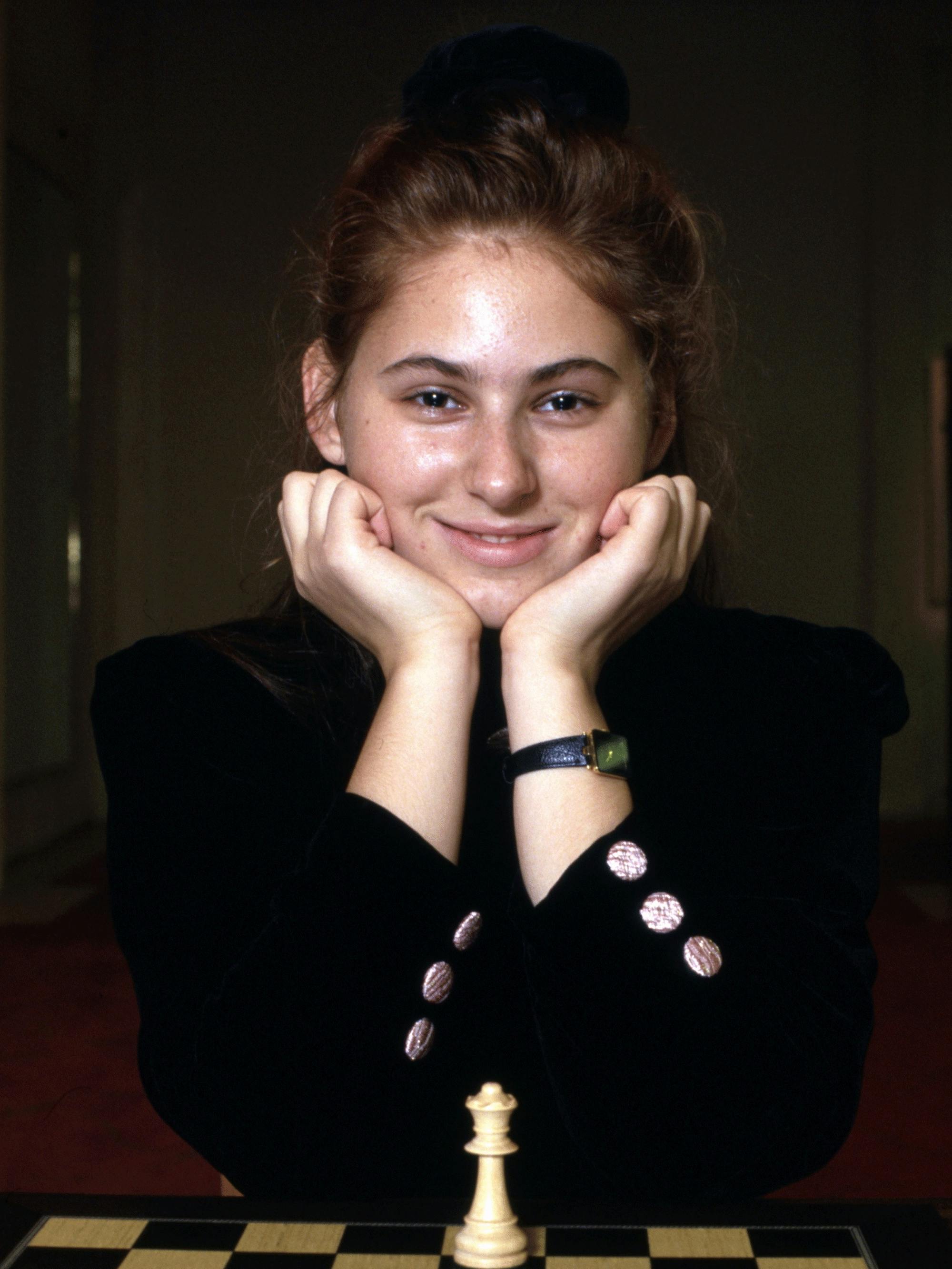 Polgár at age 15, when she became the youngest person ever to achieve the title of grandmaster. Here she wears a smart black outfit with gold buttons as she poses in front of her queen.