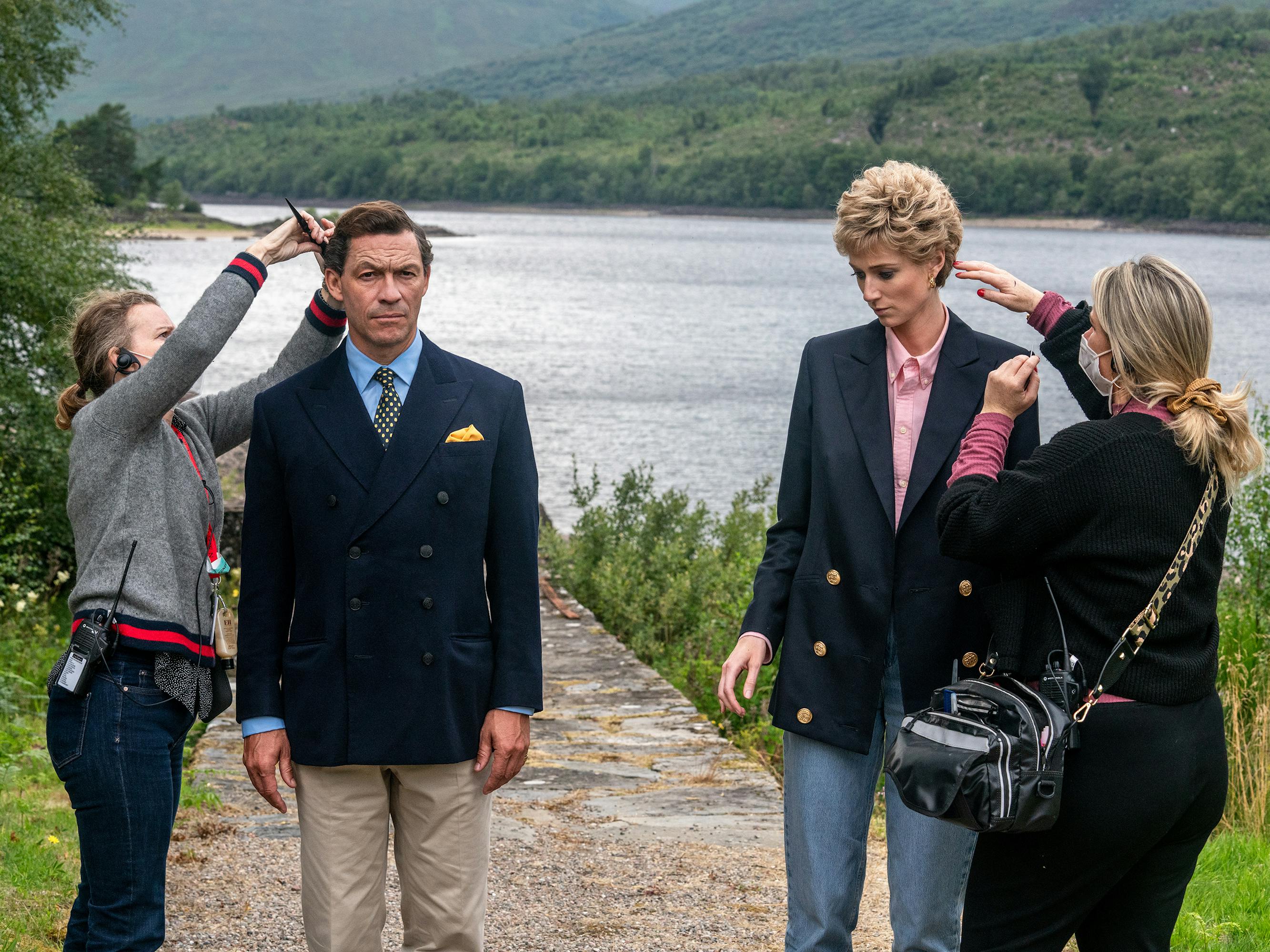 Dominic West and Elizabeth Debicki get their hair touched up by the side of a pond.