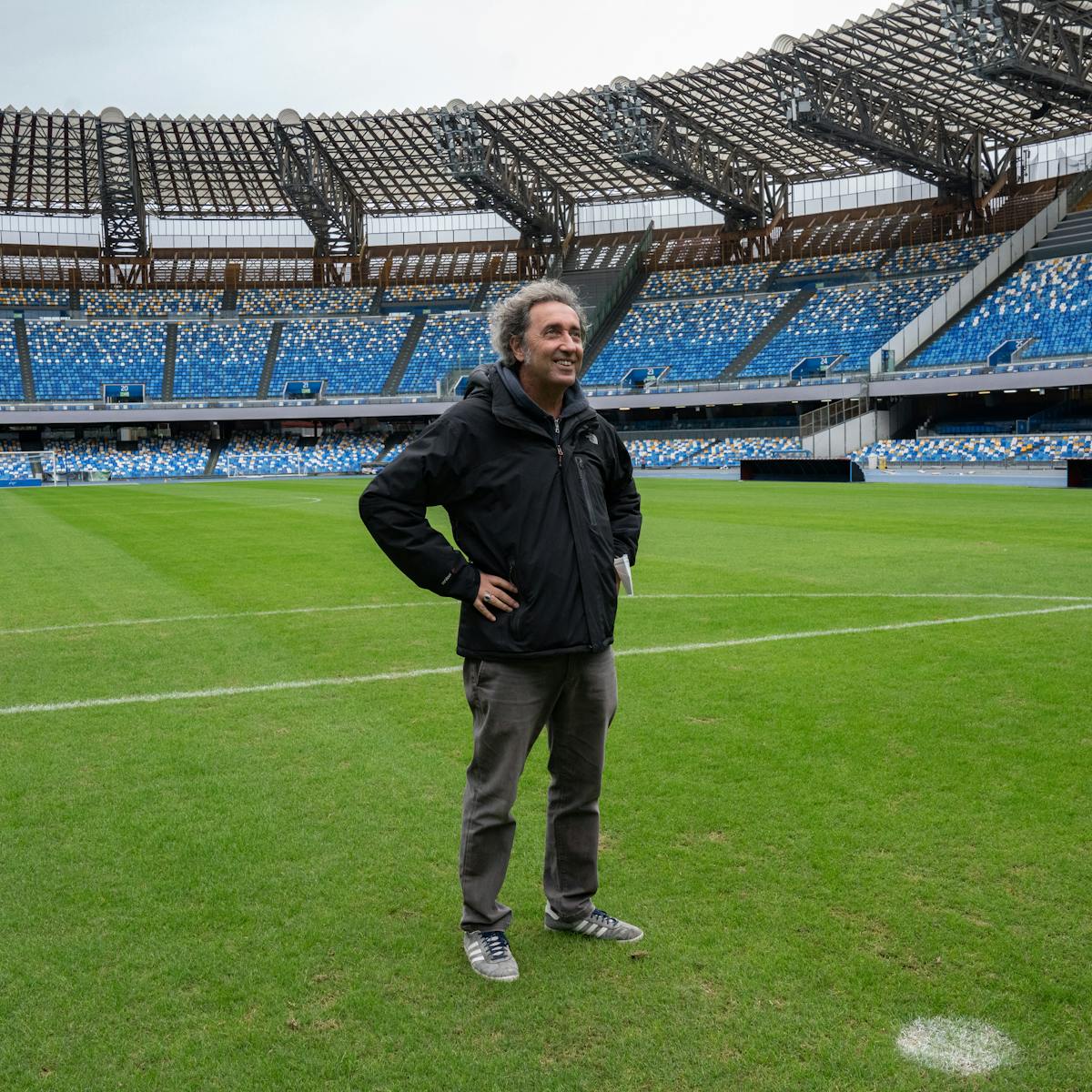 Paolo Sorrentino stands on a football pitch, hands on hips.