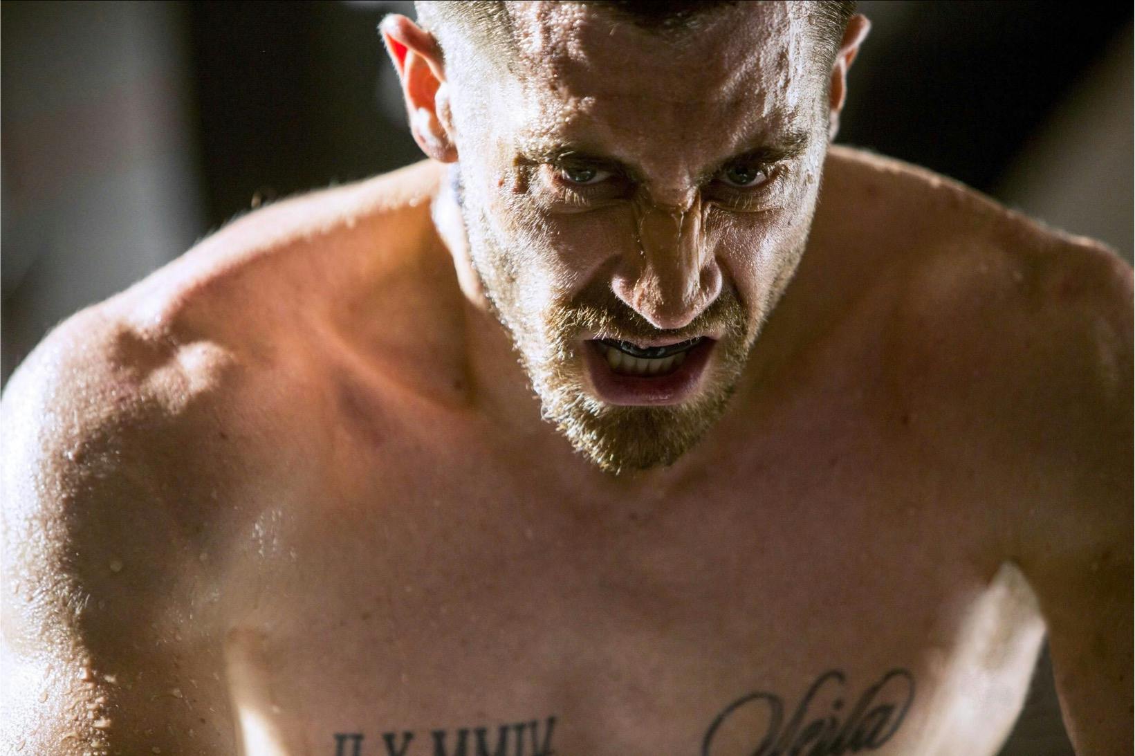 Billy Hope (Jake Gyllenhaal) in Southpaw (2015) looks intense in this close-up scene. His chest is tattooed, he wears a mouthguard, and his hair is light.