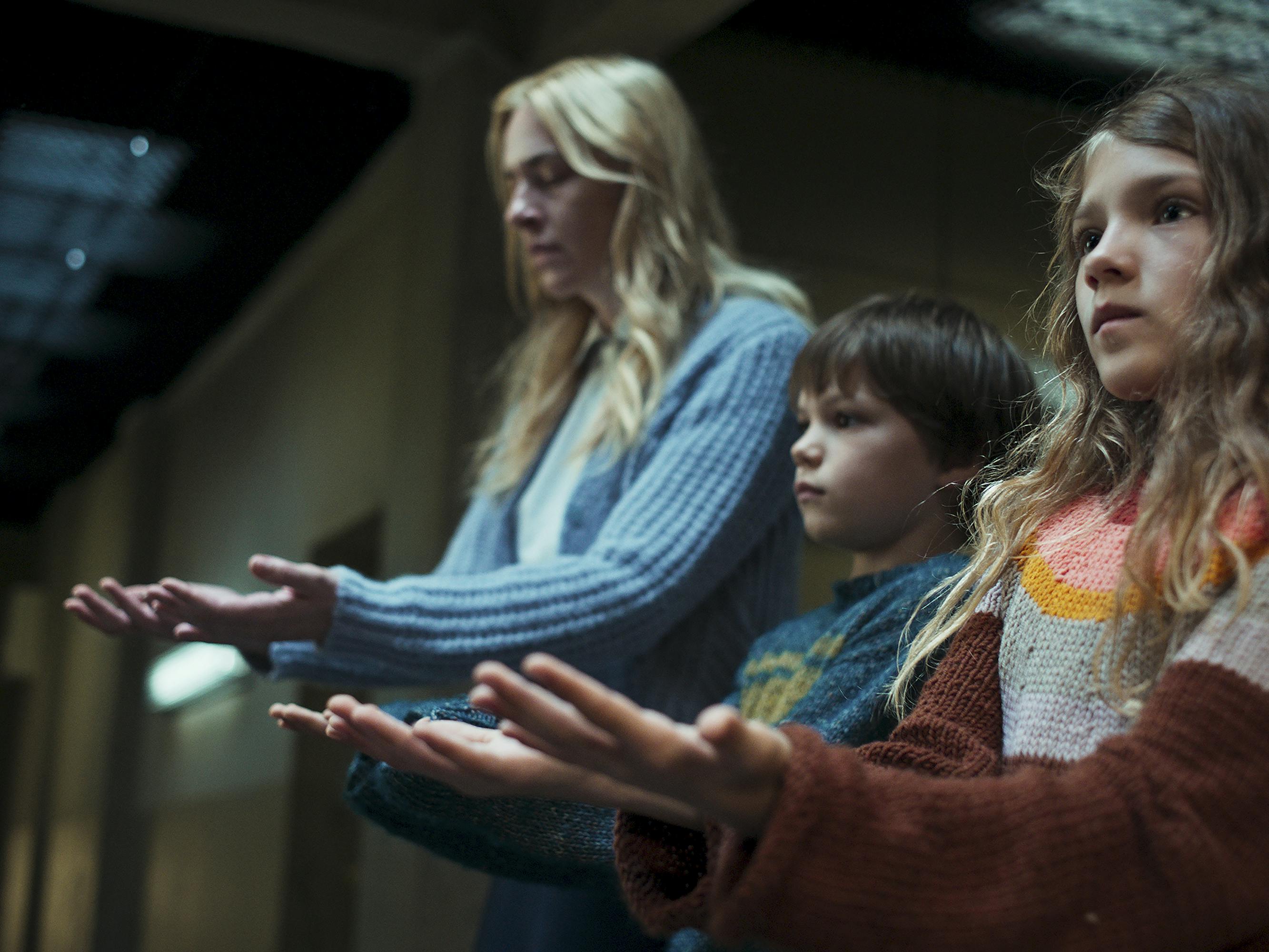 Lena (Kim Riedle), Hannah (Naila Schuberth), and Jonathan (Sammy Schrein) hold their hands out to someone offscreen.