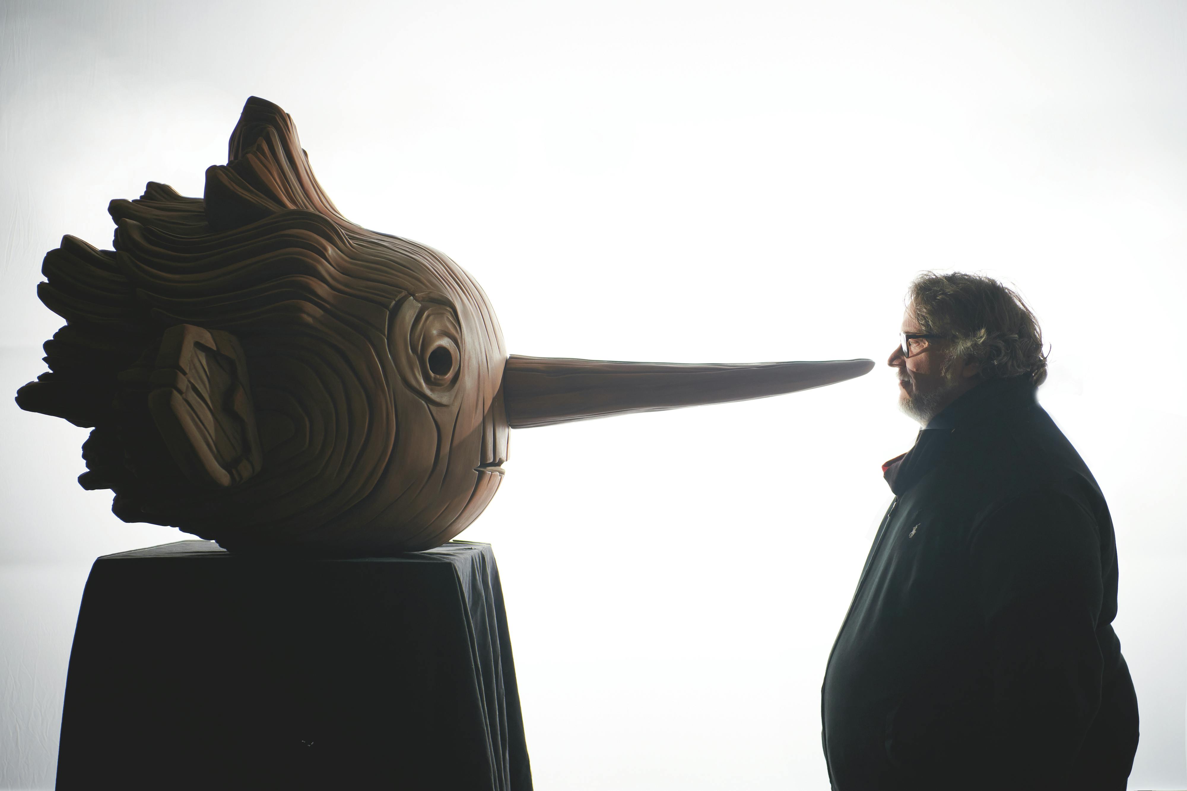 Pinocho se enfrenta al director Guillermo del Toro contra un fondo blanco.
