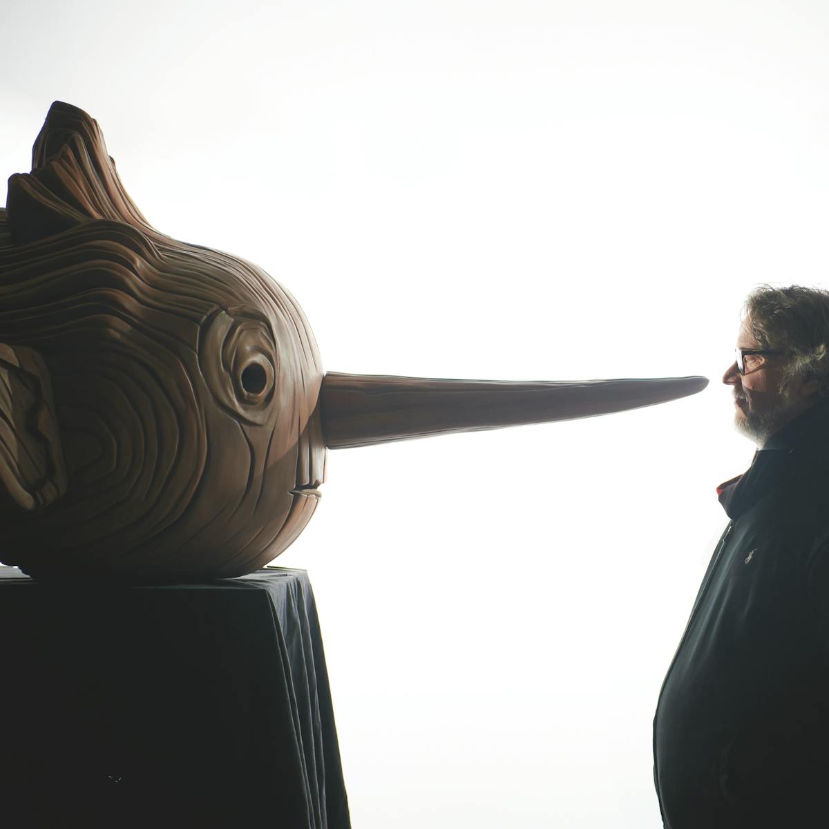 Pinocho se enfrenta al director Guillermo del Toro contra un fondo blanco.