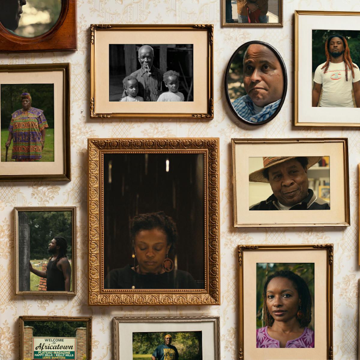 Framed photos of Africatown residents on a white wall. 
