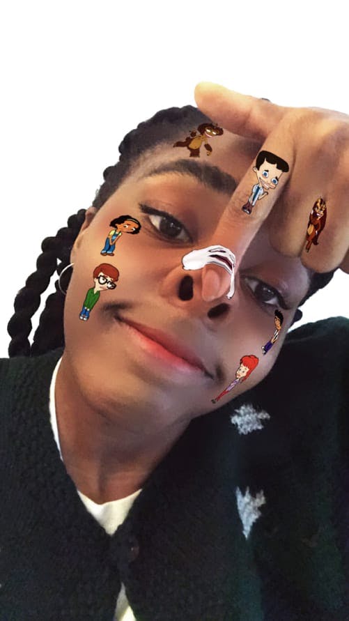 Ayo Edebiri, the new voice of the character Missy on Big Mouth, takes a selfie with stickers of the show’s animated characters decorating her face.