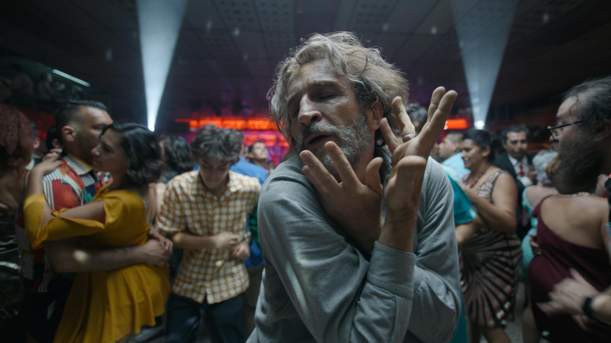 Daniel Giménez Cacho dances in a crowd of people.