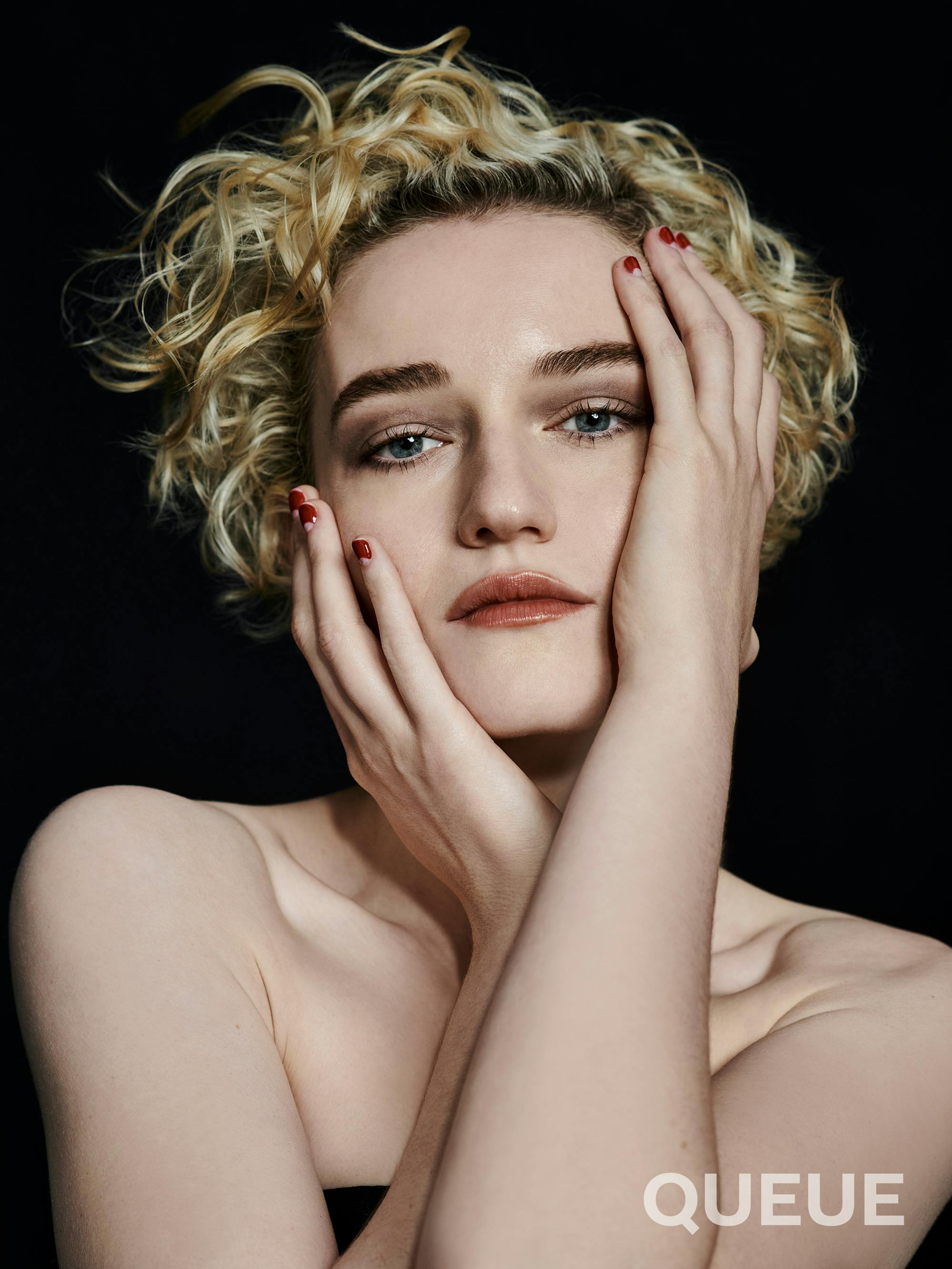 Julia Garner strikes an interesting pose with her arms wrapped around her face.