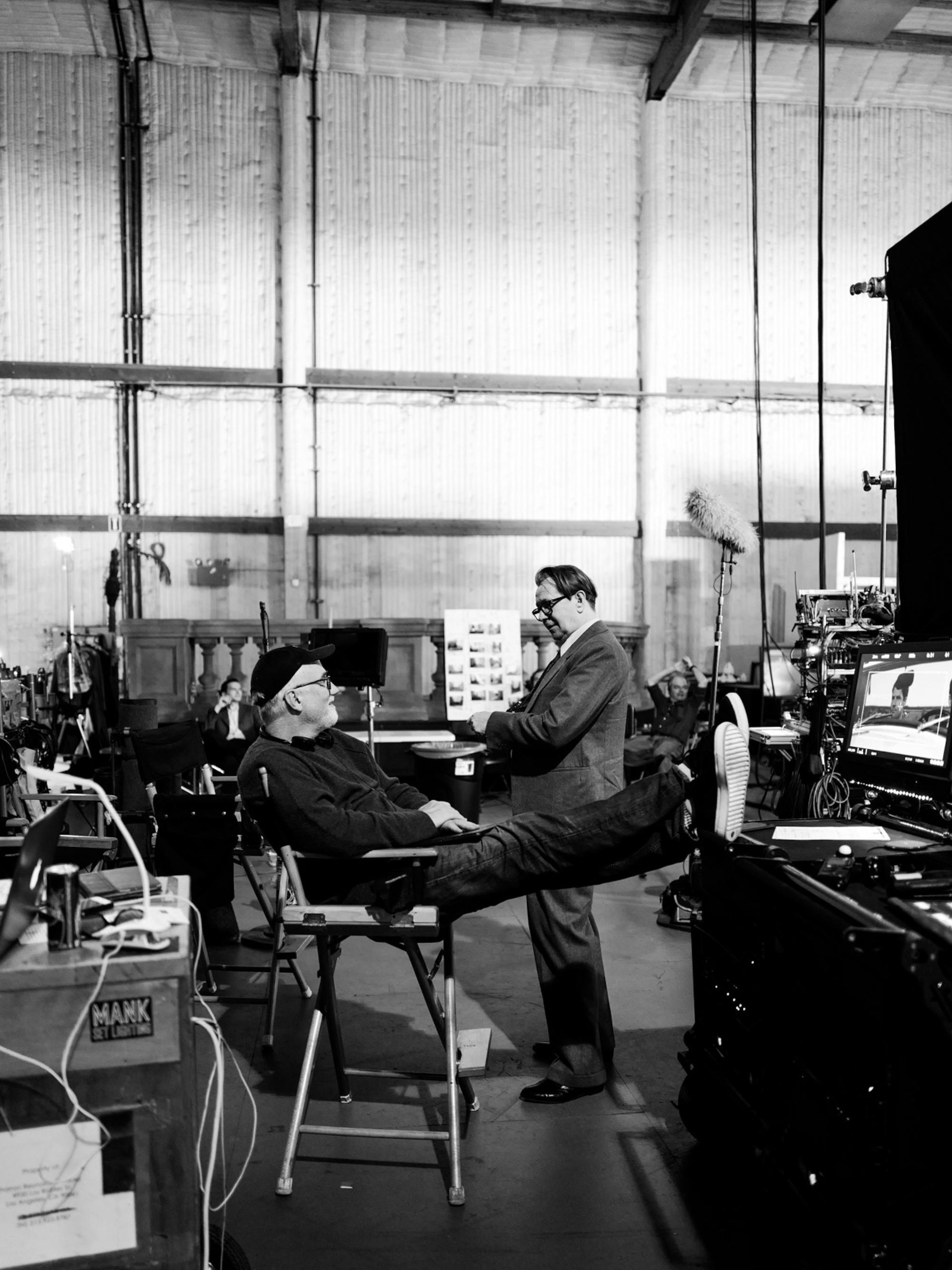 Fincher and Oldman have a chat. Fincher sits in his director’s chair, feet up on a table. Oldman stands a few feet in front of him, in costume as Herman Mankiewicz. 