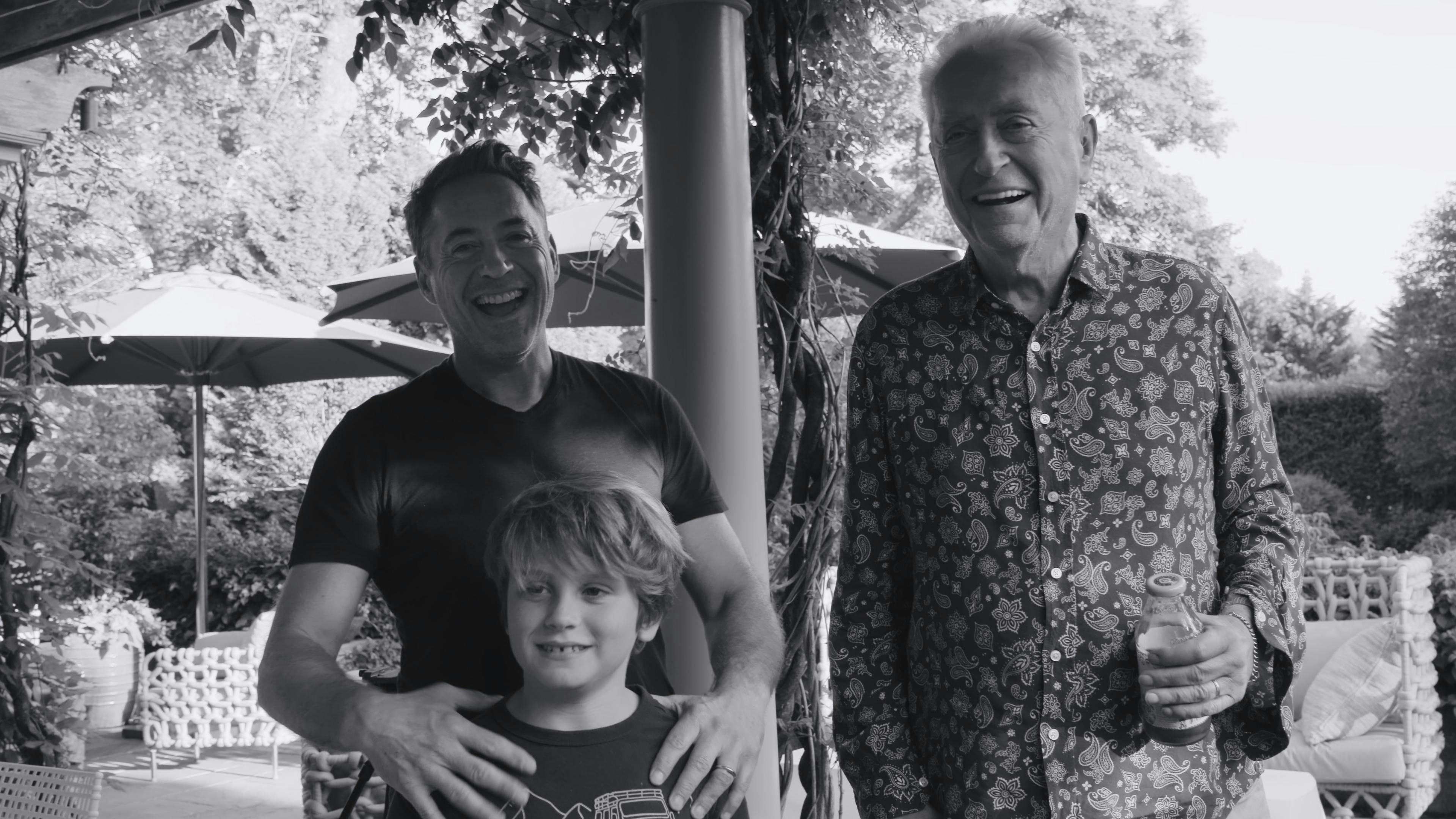 Robert Downey Jr., Exton, and Robert Downey Sr. stand together smiling in this black-and-white photo.