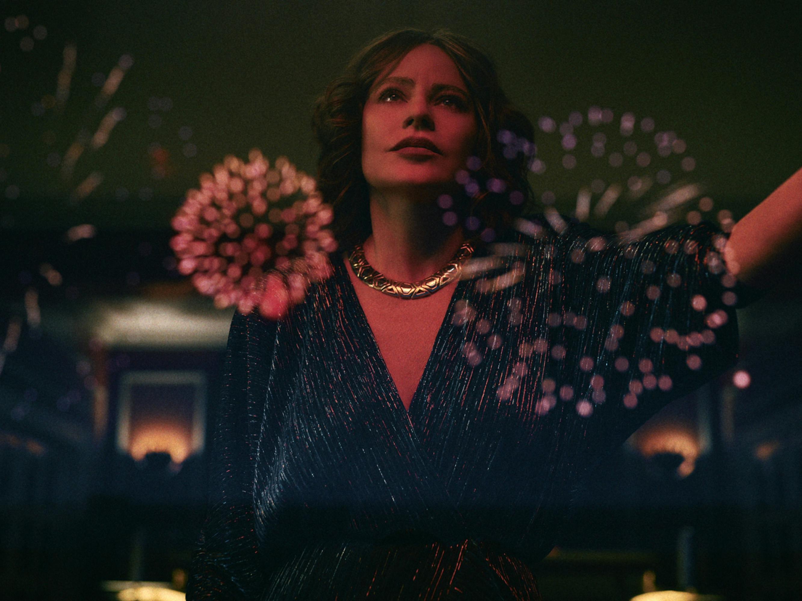 Griselda (Sofia Vergara) stands in front of a window, with the reflection of fireworks lighting up her face.