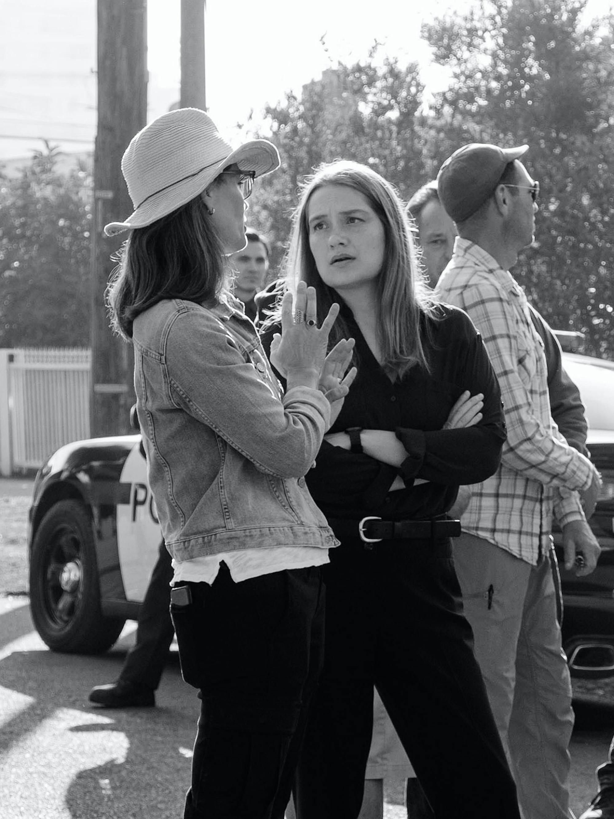 Susannah Grant and Merritt Wever stand near police cars in this black-and-white shot.