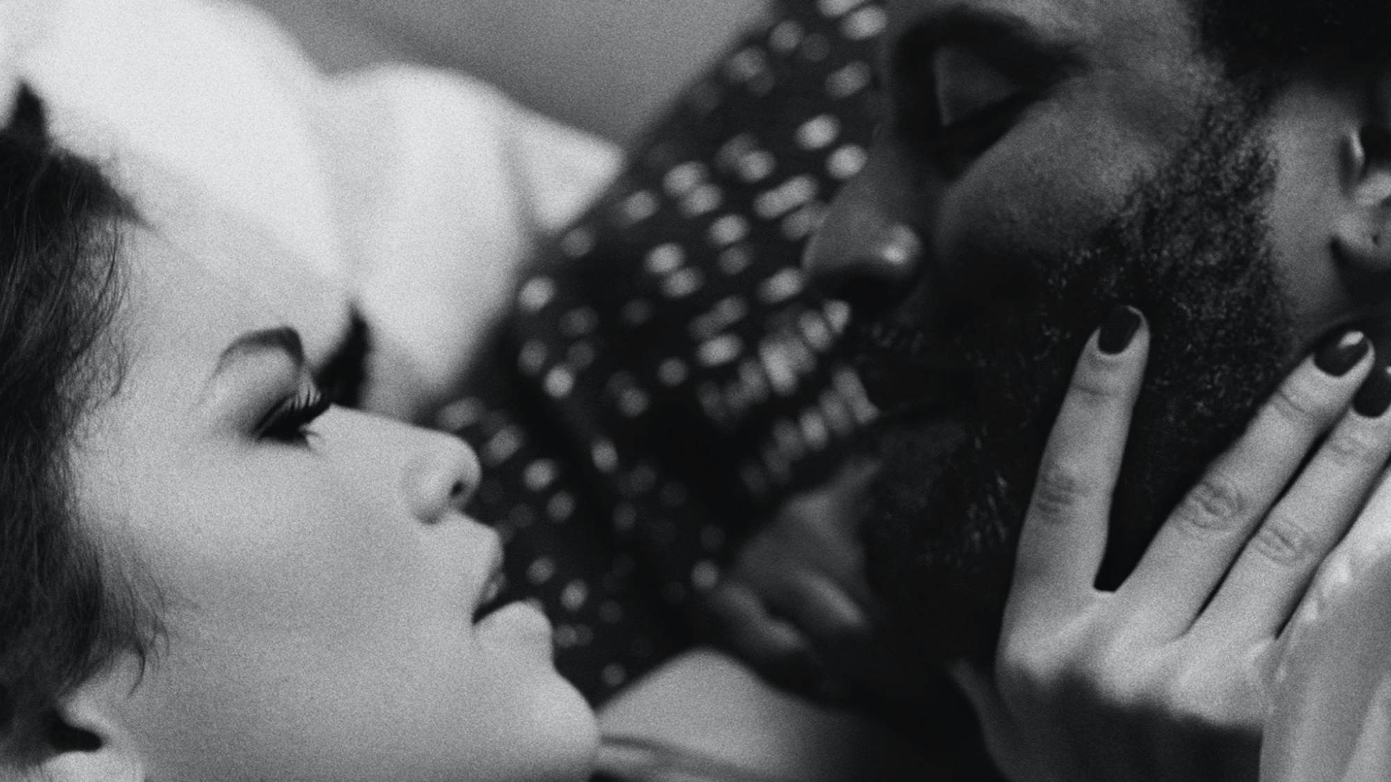 A still from Malcolm & Marie shows the film’s protagonists in closeup. Marie and Malcolm appear in profile, looking into each other’s faces. Marie holds Malcolm’s chin.
