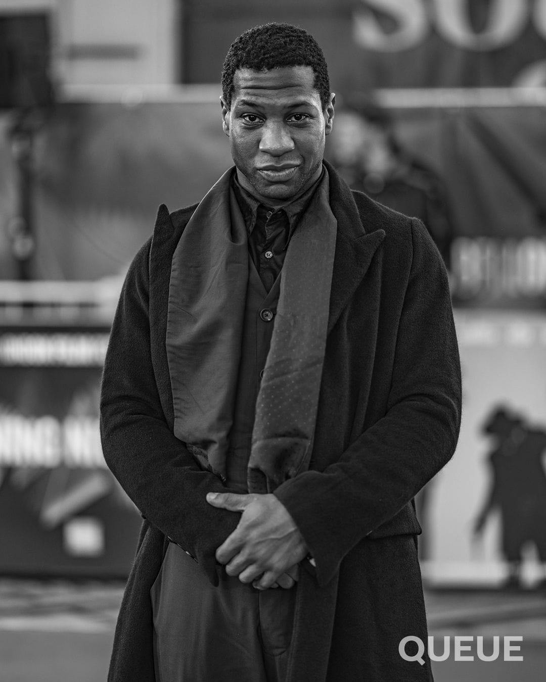 Jonathan Majors looks straight into the camera on the red carpet