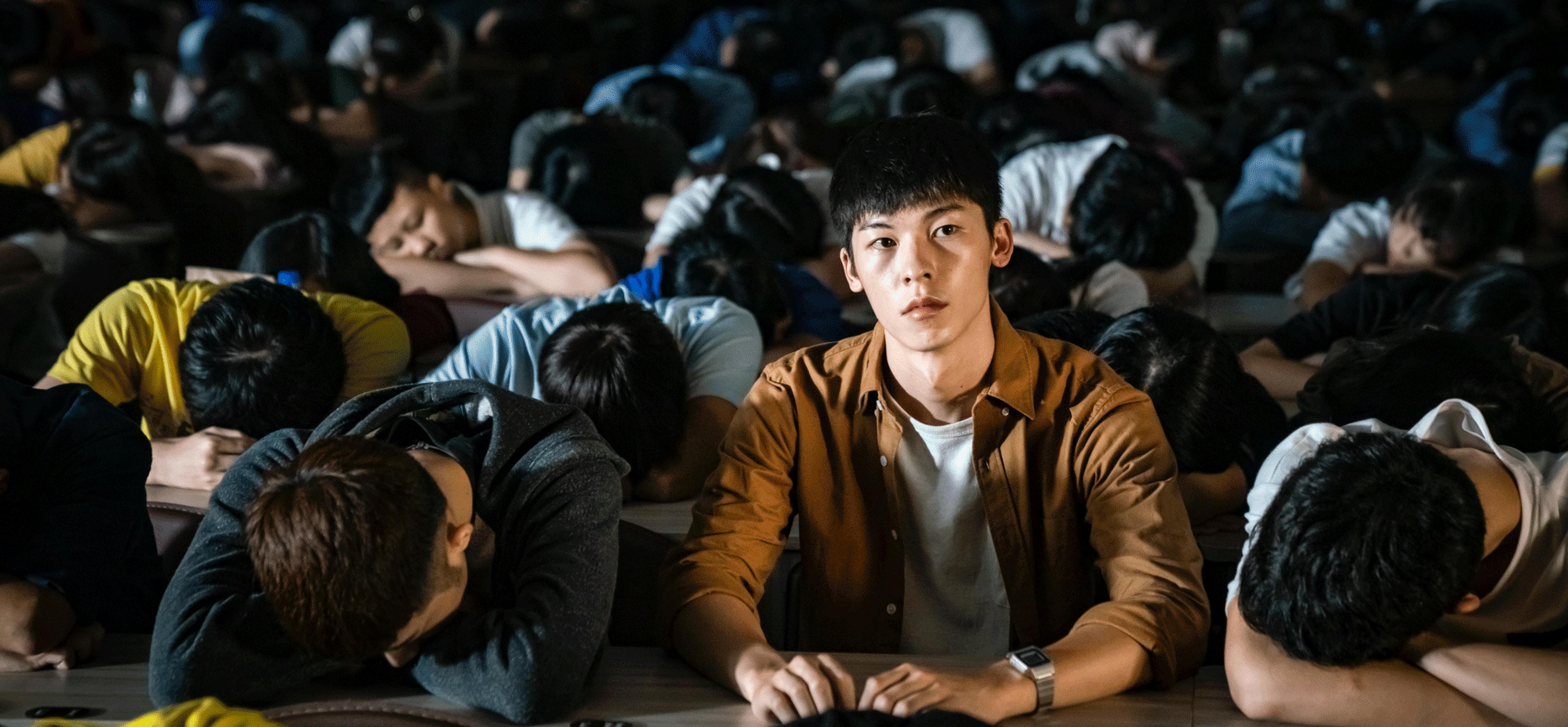 Hsu Kuang-han as A-hao in A Sun. This still from the film shows a crowd of young men, all sleeping with their heads down on their desks. Only A-hao sits upright, looking into the distance.