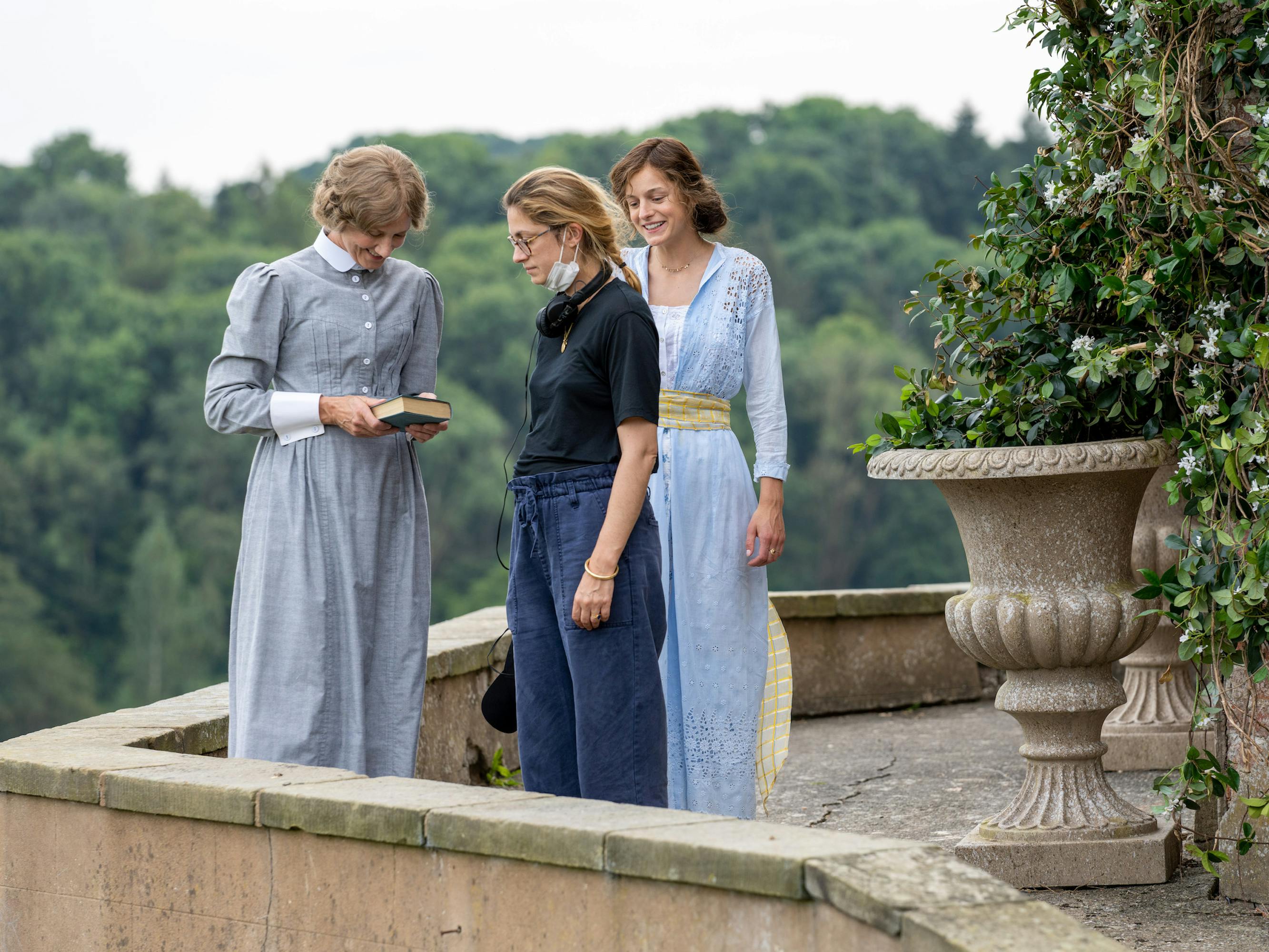 Mrs. Bolton (Joely Richardson), Laure de Clermont-Tonnerre, and Connie (Emma Corrin) wear various shades of blue and stand on a porch against a forest backdrop.