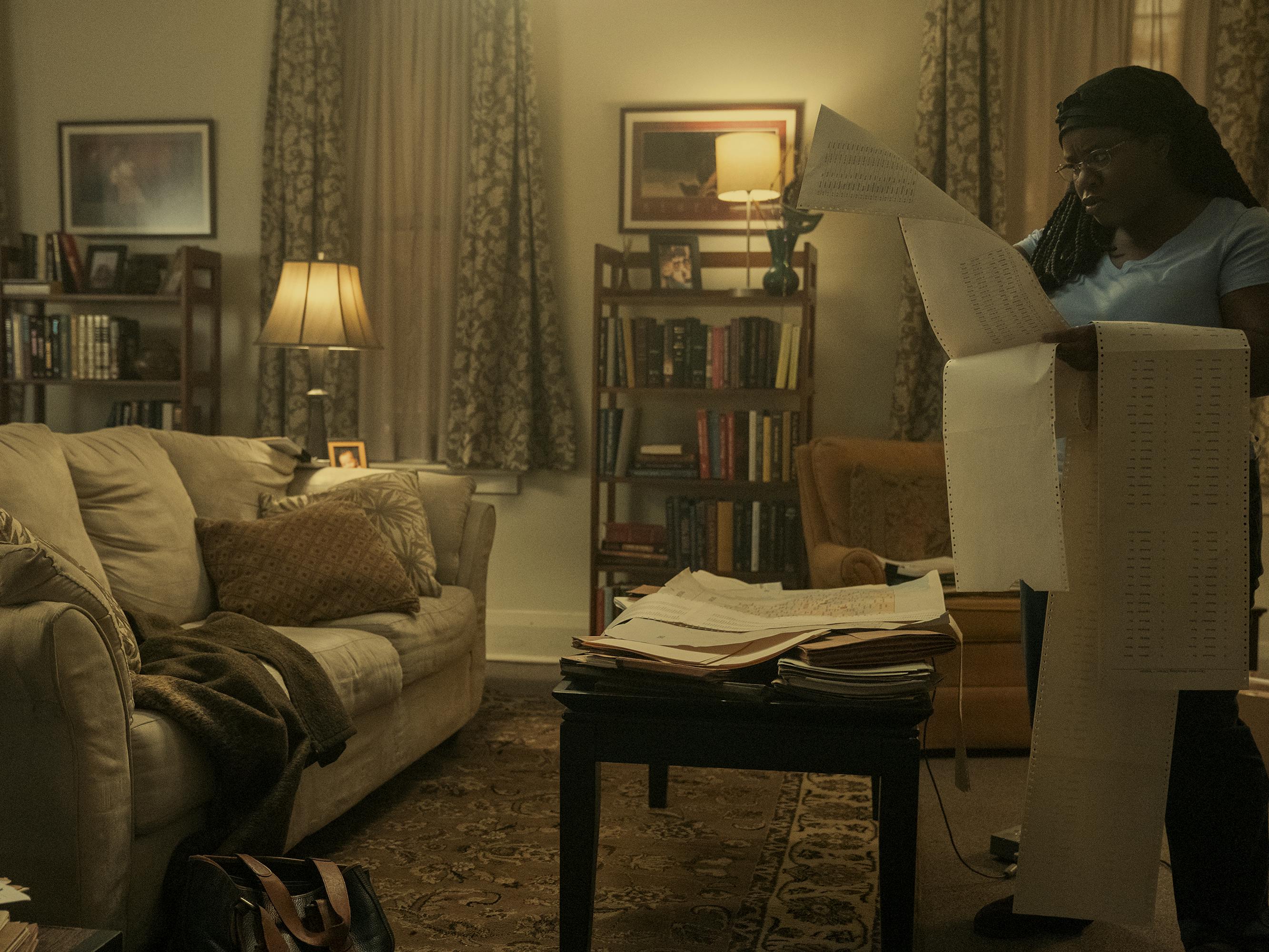 Edie Flowers (Uzo Aduba) reads some very long pieces of paper in a dimly lit, cozy living room.