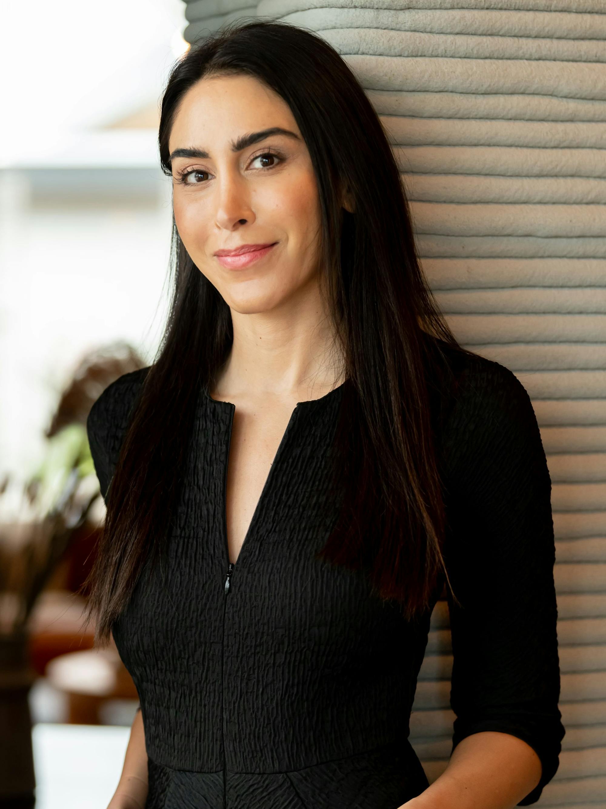 Melodie Yashar wears a black shirt and smiles softly.