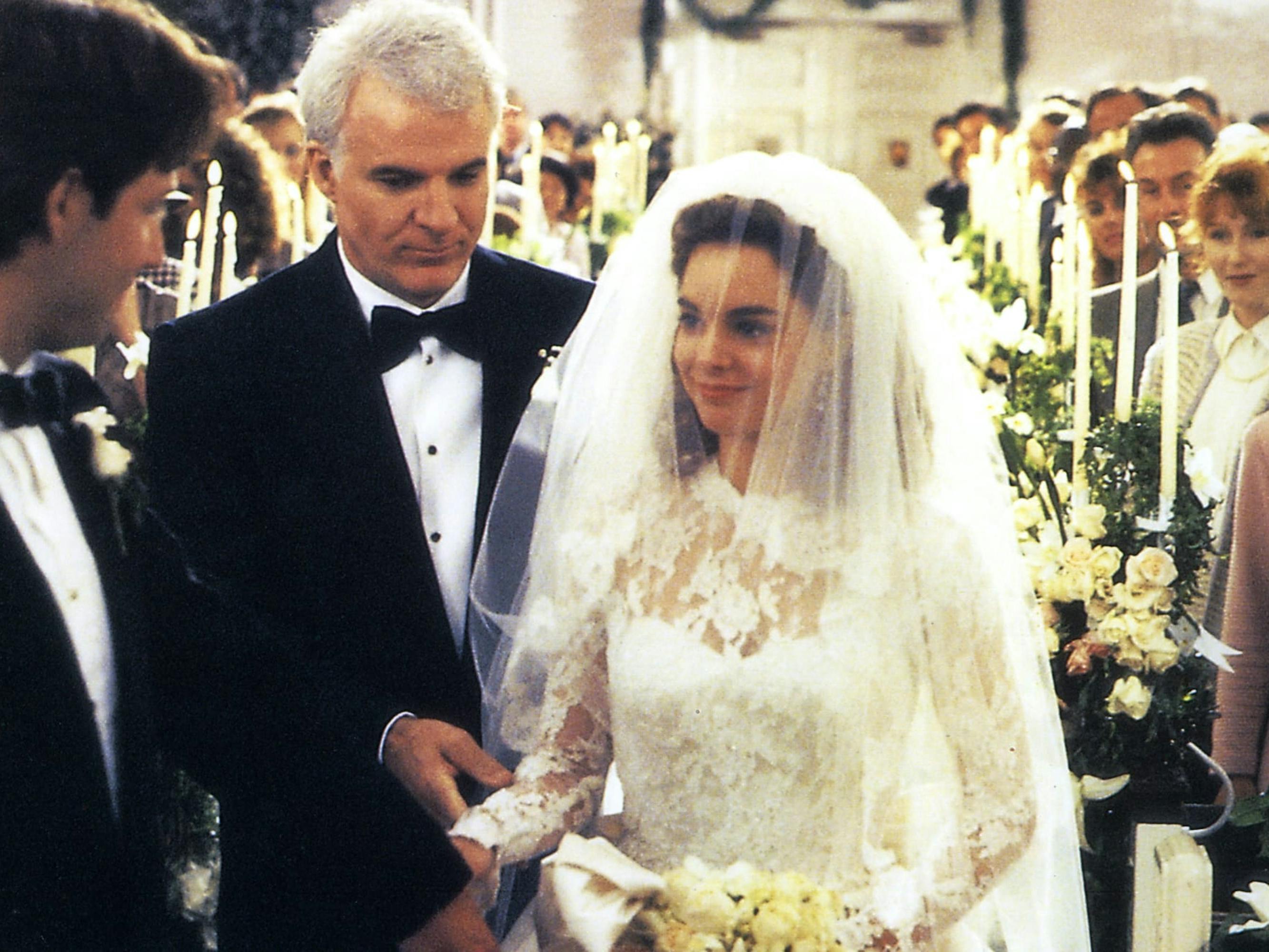 Bryan MacKenzie (George Newbern), George Banks (Steve Martin), and Annie Banks-MacKenzie (Kimberly Williams-Paisley) in Father of the Bride. The make their way down the aisle of a church, with loving family and friends smiling from the pews.