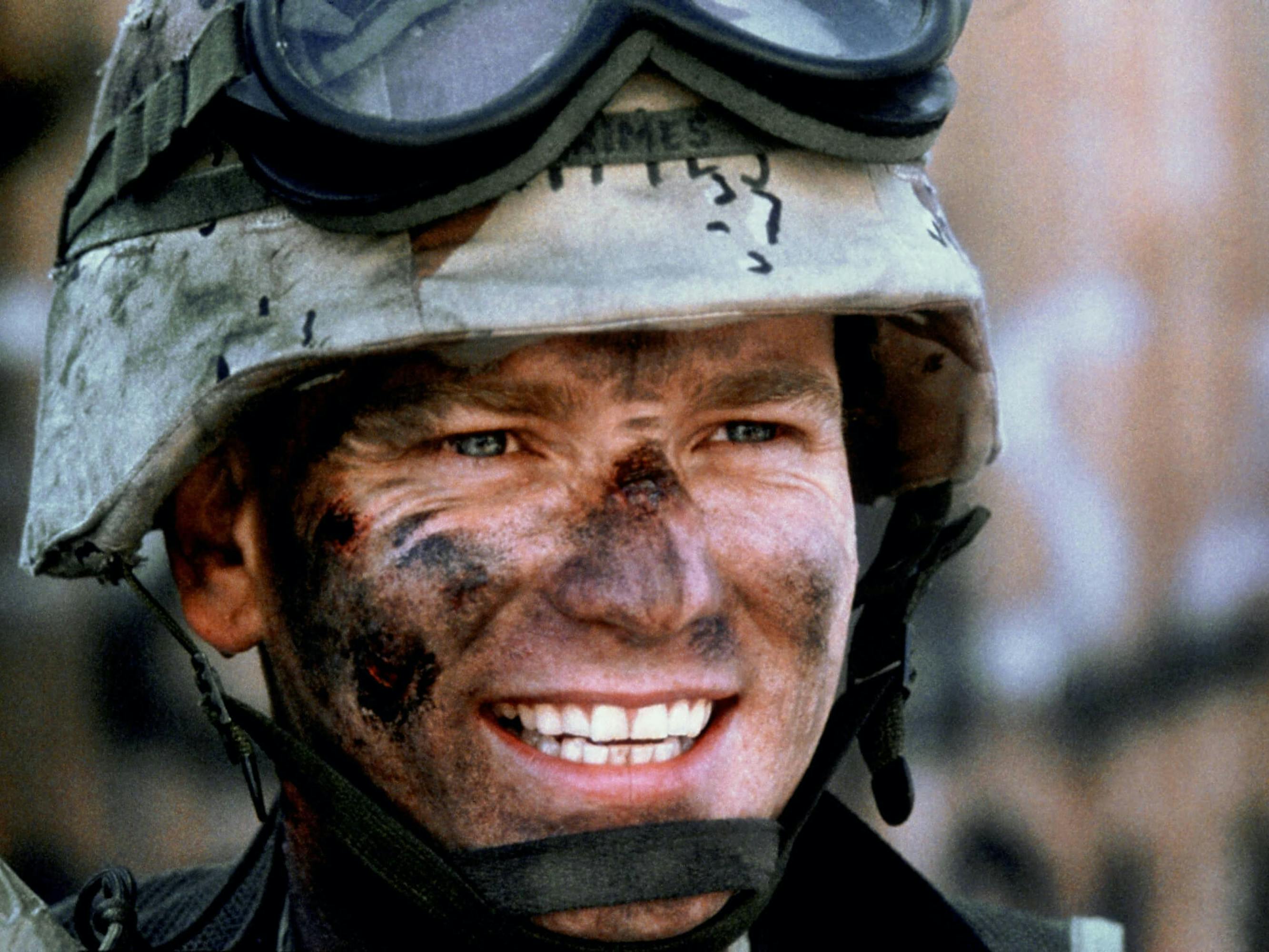 Grimes (Ewan McGregor) in Black Hawk Down smiles from underneath an army helmet, his face streaked with dark paint.