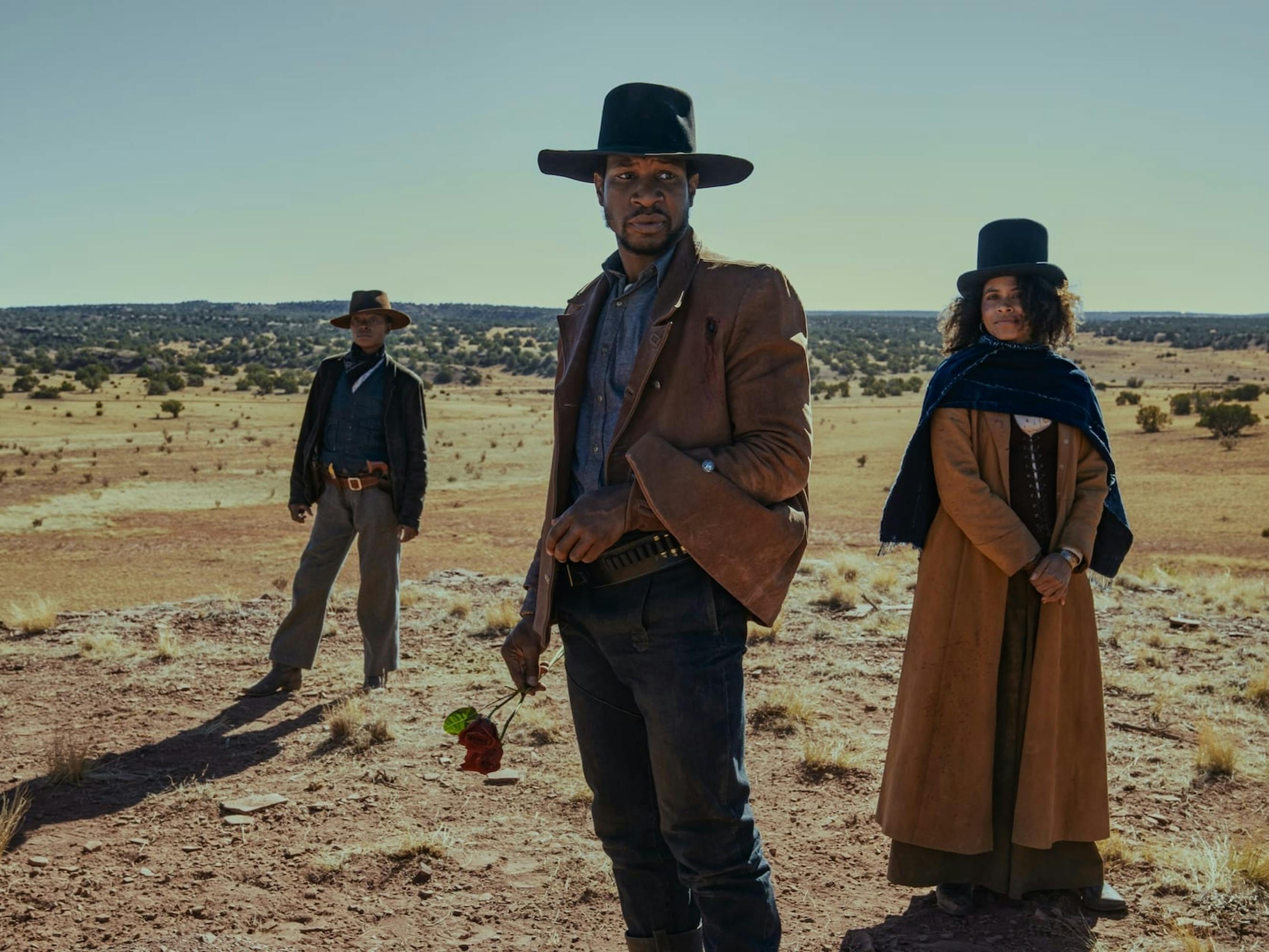 Cuffee (Danielle Deadwyler), Nat Love (Jonathan Majors), and Stagecoach Mary (Zazie Beetz) stand in a deserted dusty spot. Behind them, small bushes dot the landscape.