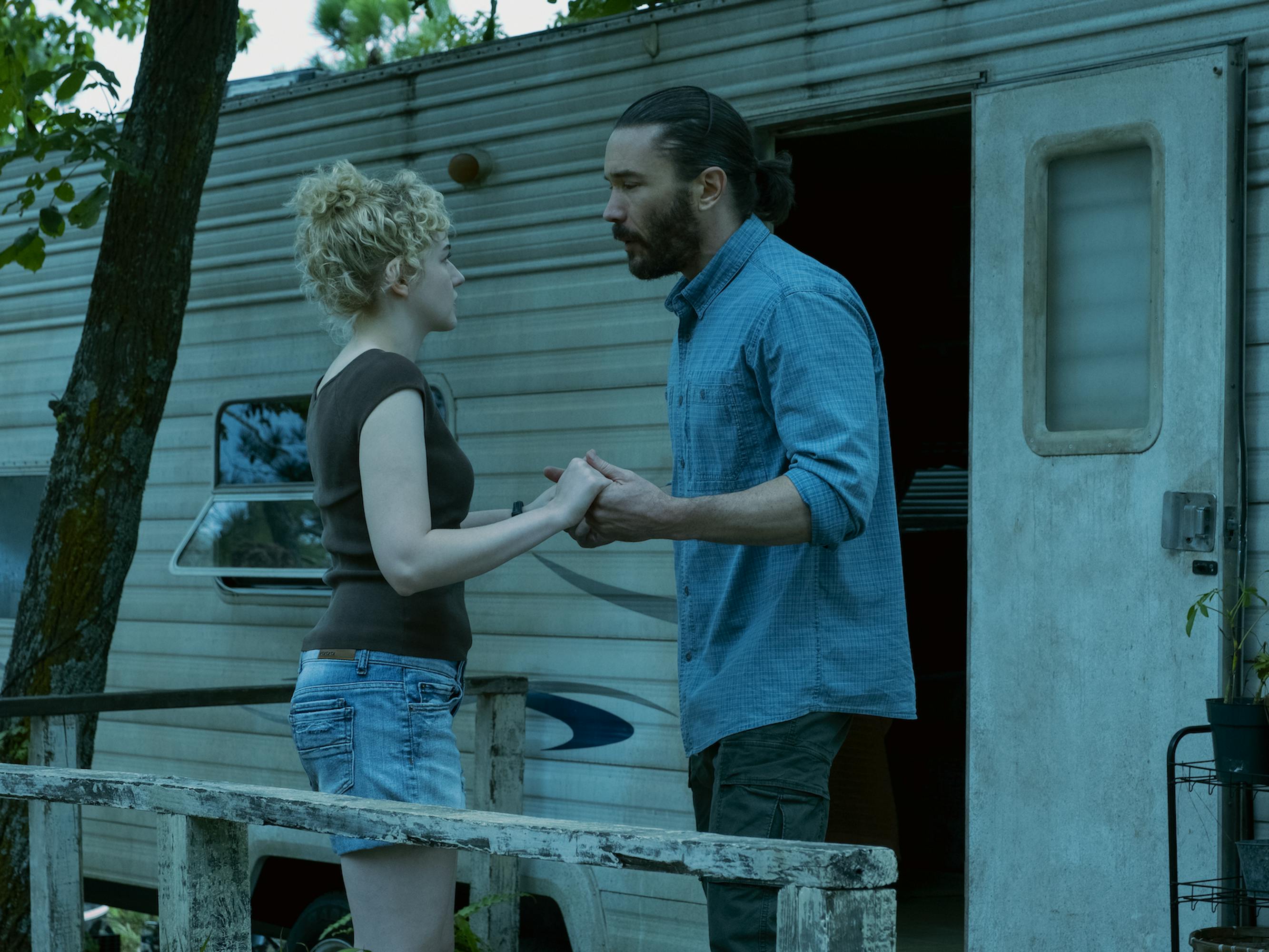 Ruth Langmore (Julia Garner) and Ben Davis (Tom Pelphrey) argue outside a trailer. Garner wears cut offs and an olive t-shirt, Davis wears a jean shirt and green pants.