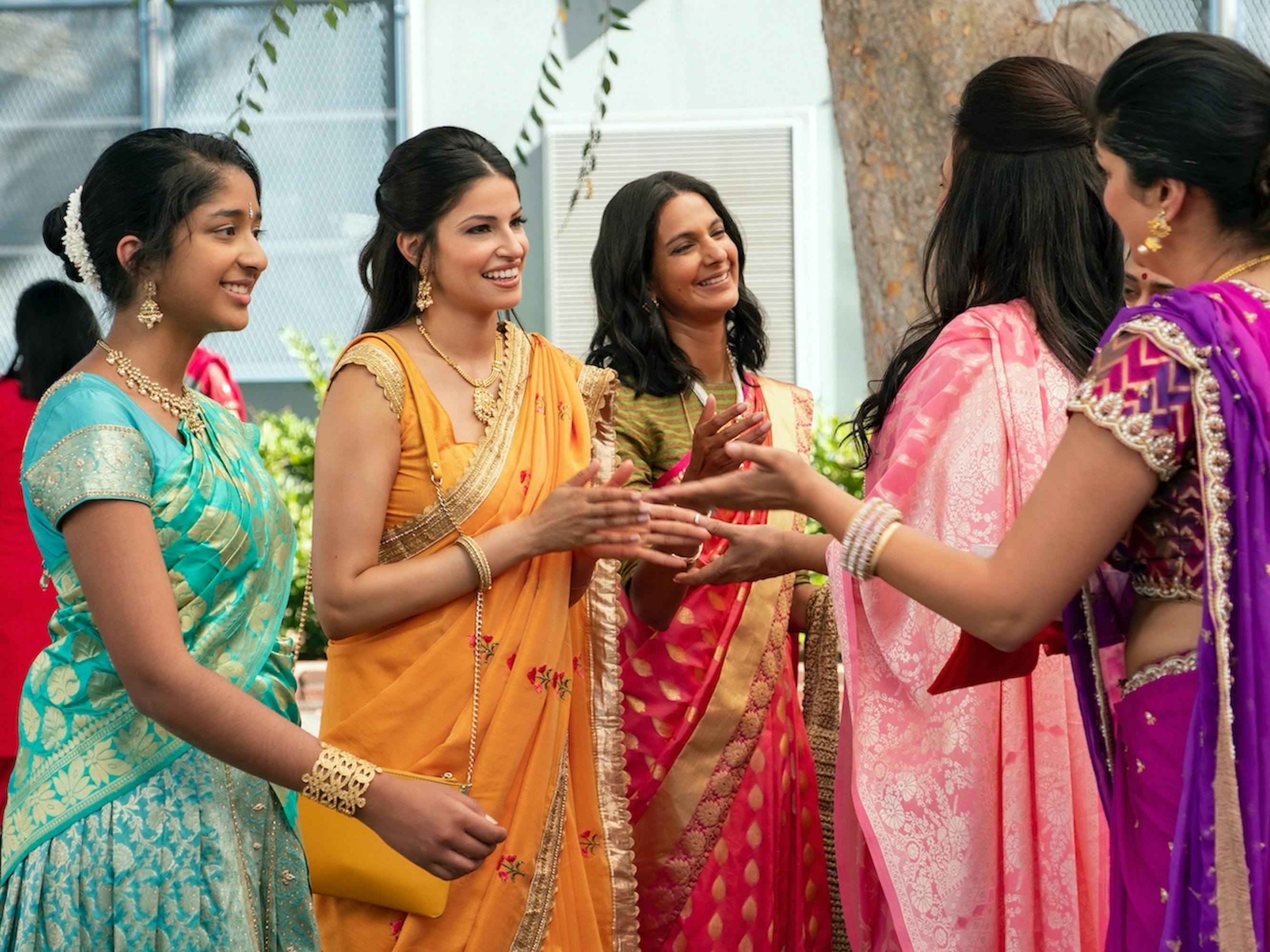 Devi Vishwakumar (Maitreyi Ramakrishnan) Kamala (Richa Moorjani), Nalini Vishwakumar (Poorna Jagannathan), Jaya Kuyavar (Aarti Mann), and Auntie (Alice Amter) wear beautiful saris in turquoise, orange, red, pink, and purple. They embrace each other.