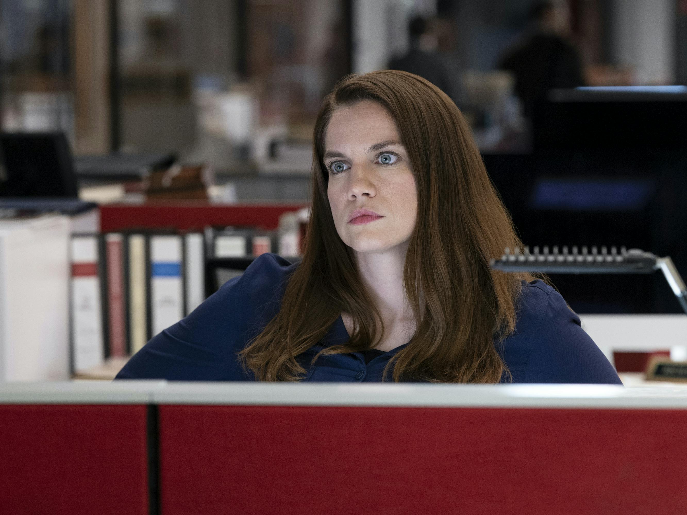 Vivian Kent (Anna Chlumsky) sits in a red booth surrounded by binders.