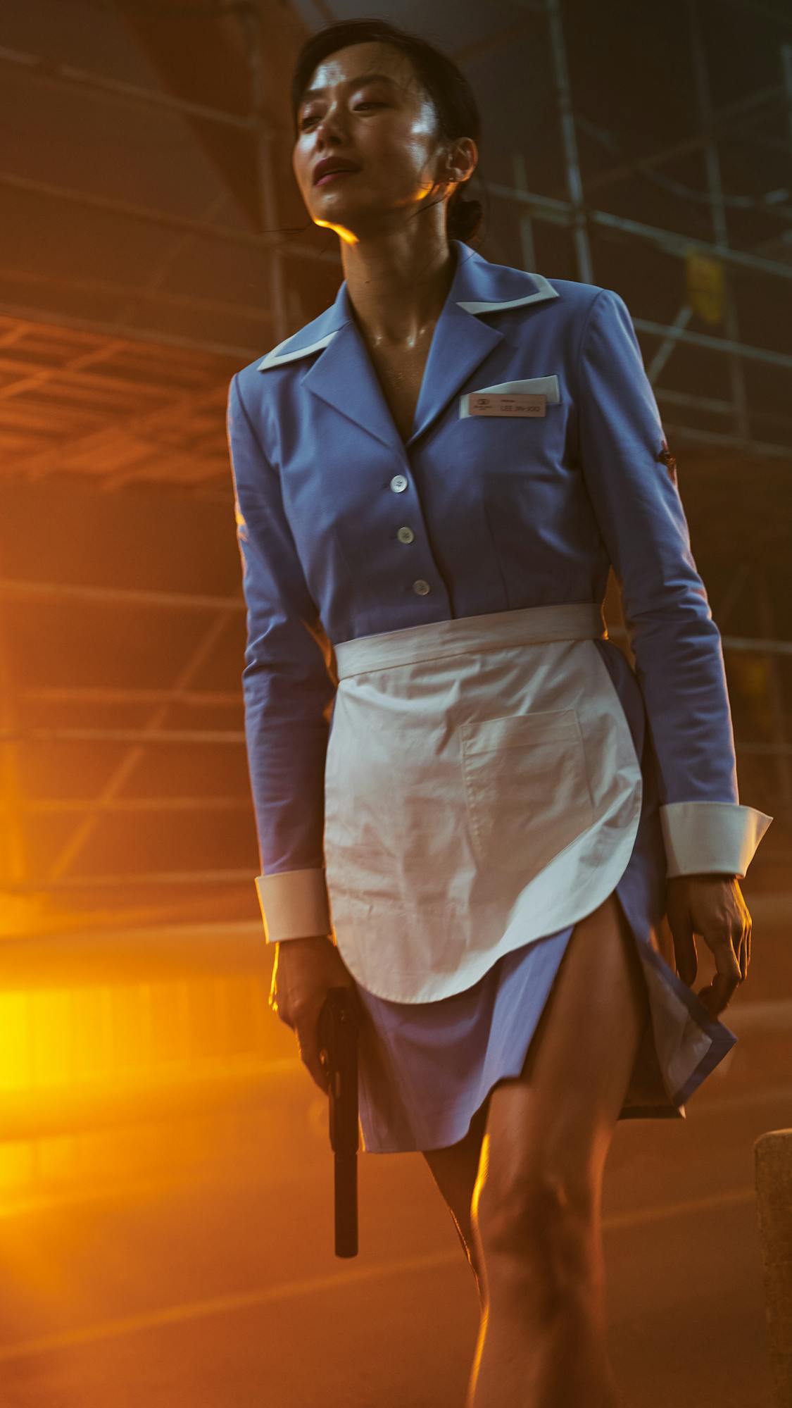 Jeon Do-yeon wears a blue and white waitress or maid uniform and holds a gun 
