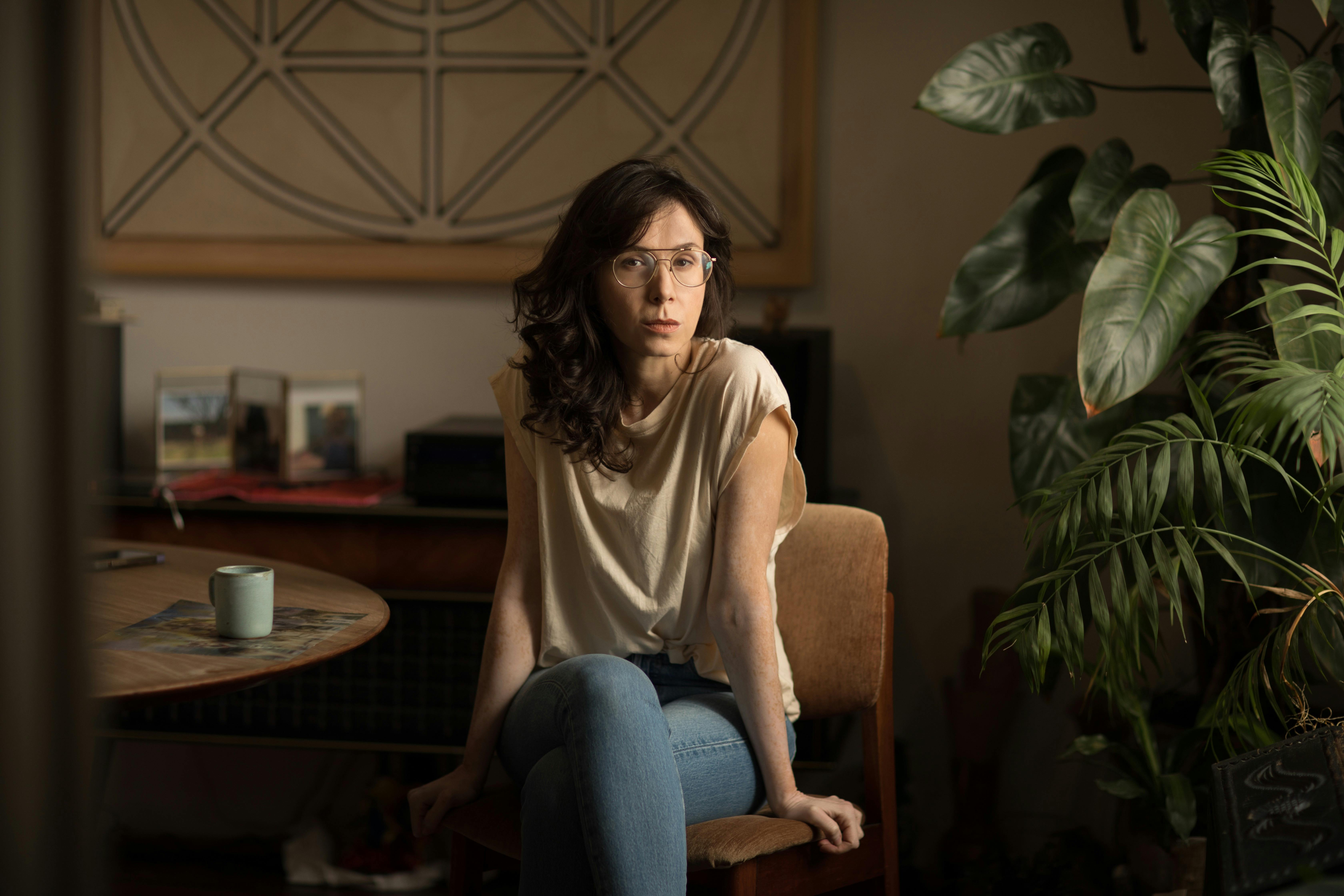 Natalia Beristain wears jeans and a tan top, and sits in at a table with a coffee cup.