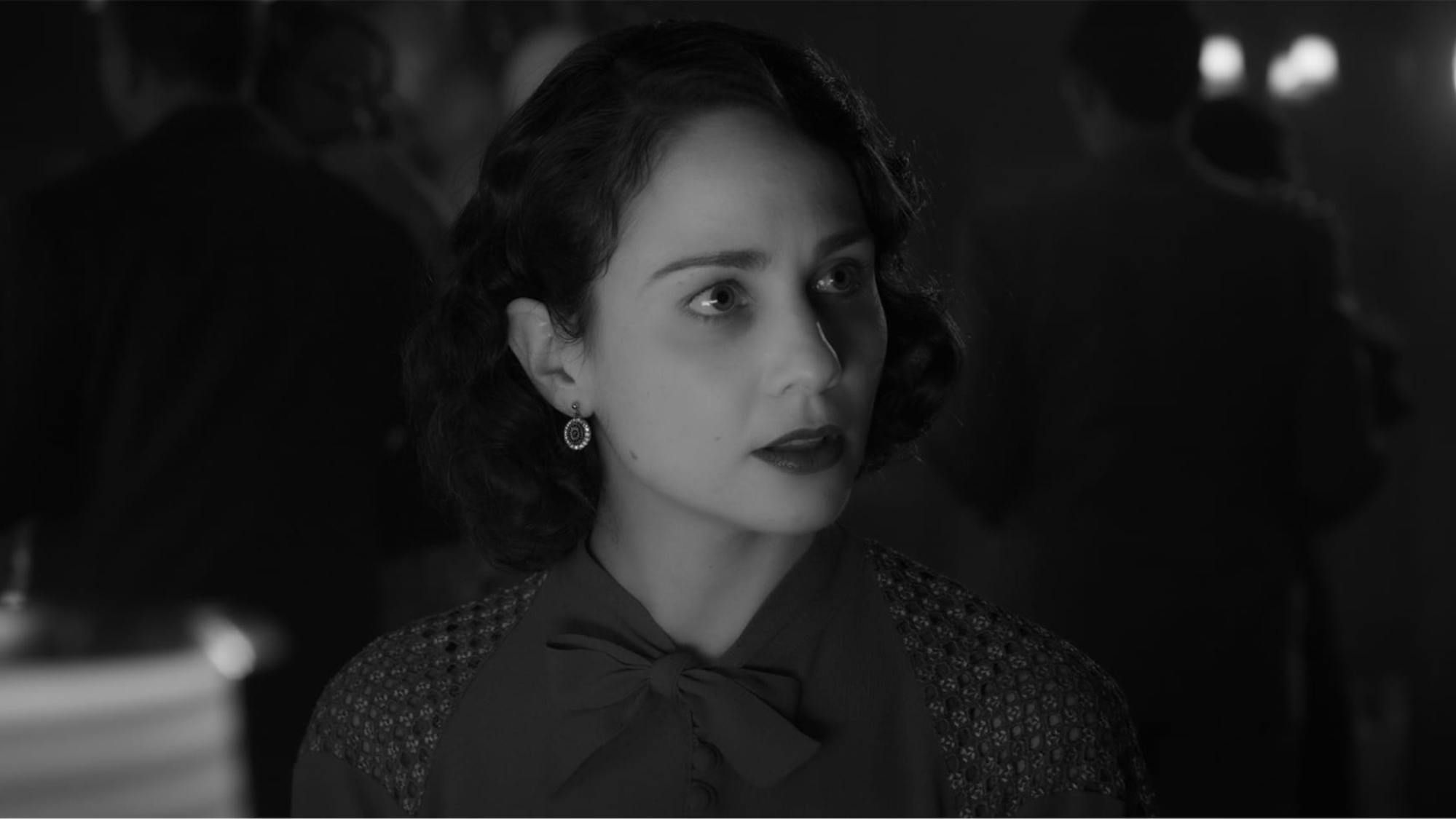In a shot from the film, we see how the scene above translates to a black-and-white experience. Middleton’s dark hair, red dress, and red lipstick appear in rich shades of gray and black. 