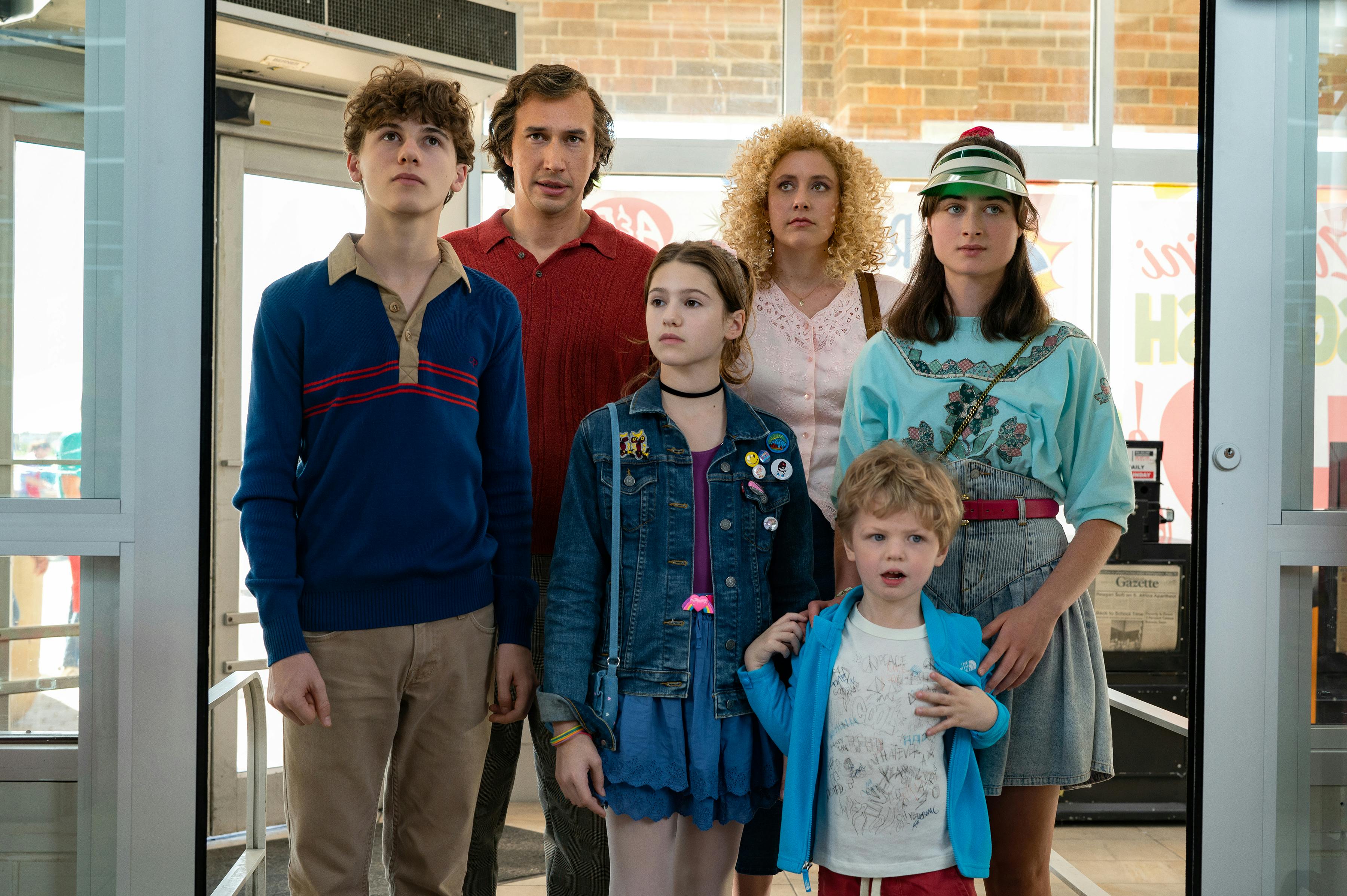 The Gladney family led by parents Jack Gladney (Adam Driver) and Babette (Greta Gerwig). The four kids wear different shades of blue and look very 80s. 