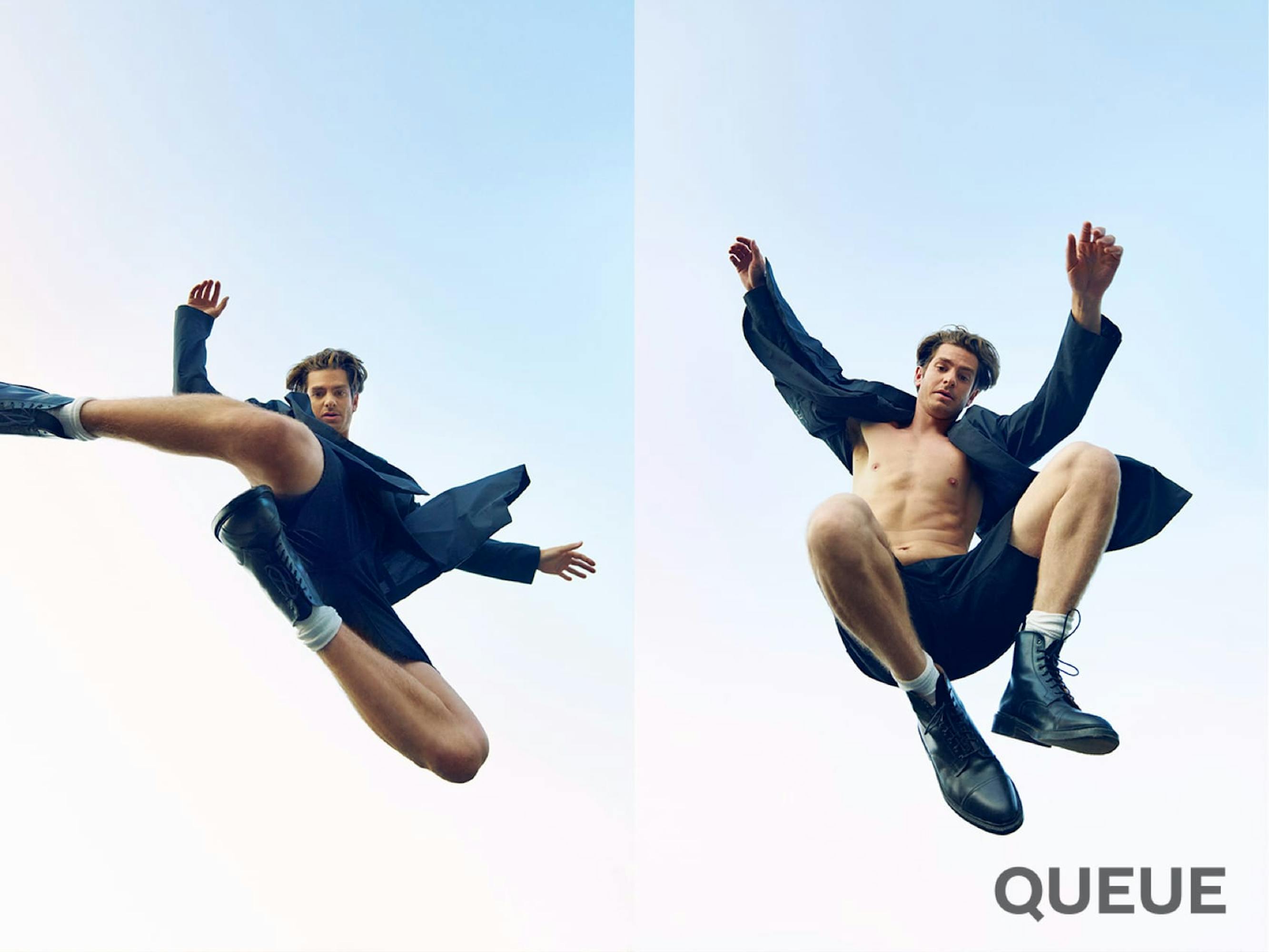 Andrew Garfield jumps into the air in this diptych shot. He wears a dark jacket, dark shorts, no shirt, and big black boots. The sky is a clear blue.