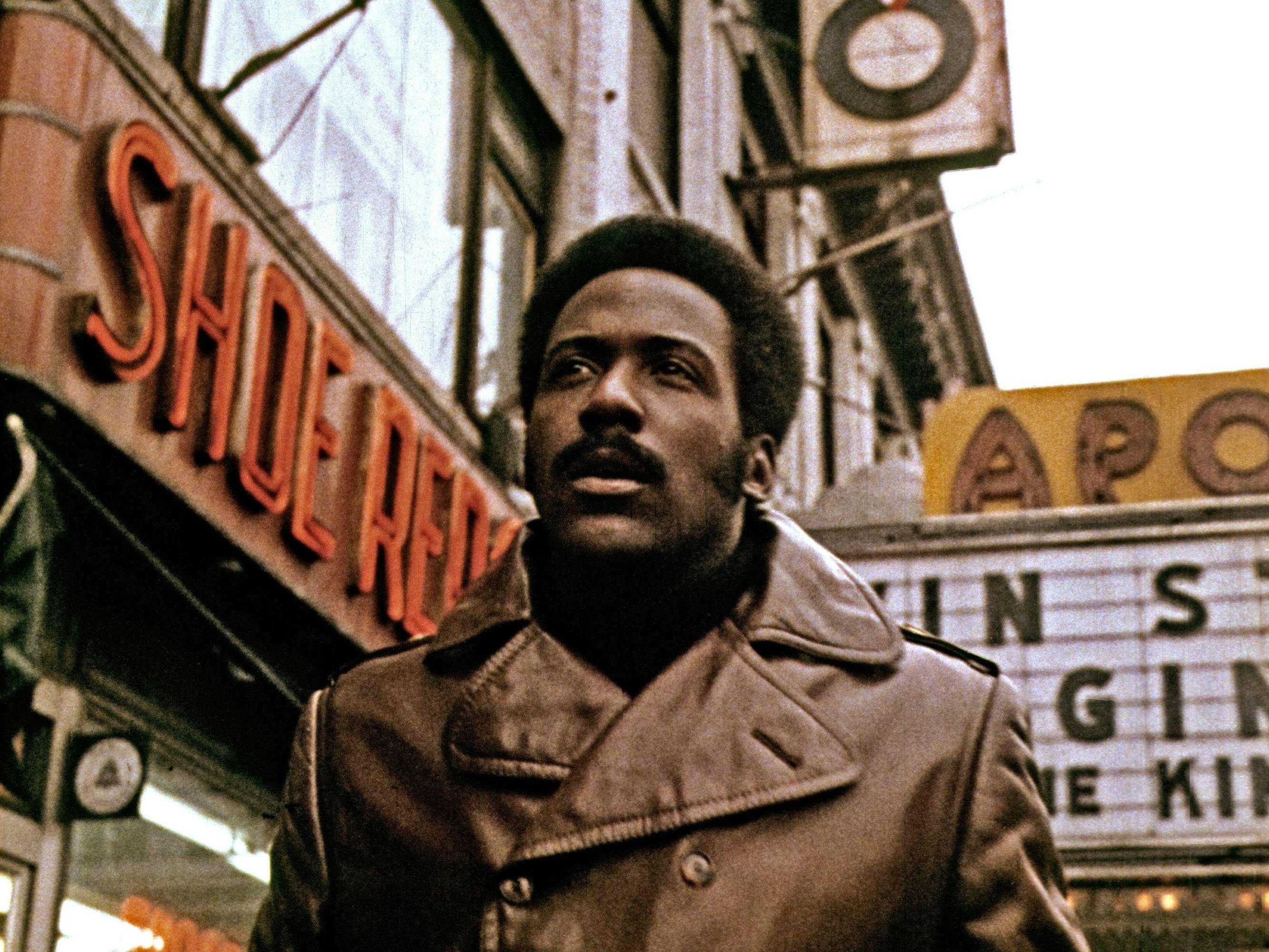 John Shaft (Richard Roundtree) wears a brown leather jacket and walks through New York City. 
