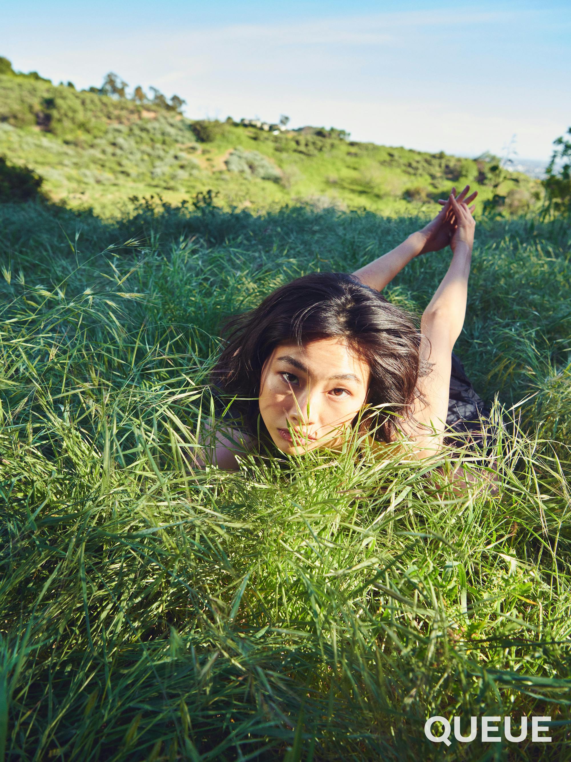 Jung Ho-yeon lies in the grass with her arms outstretched.