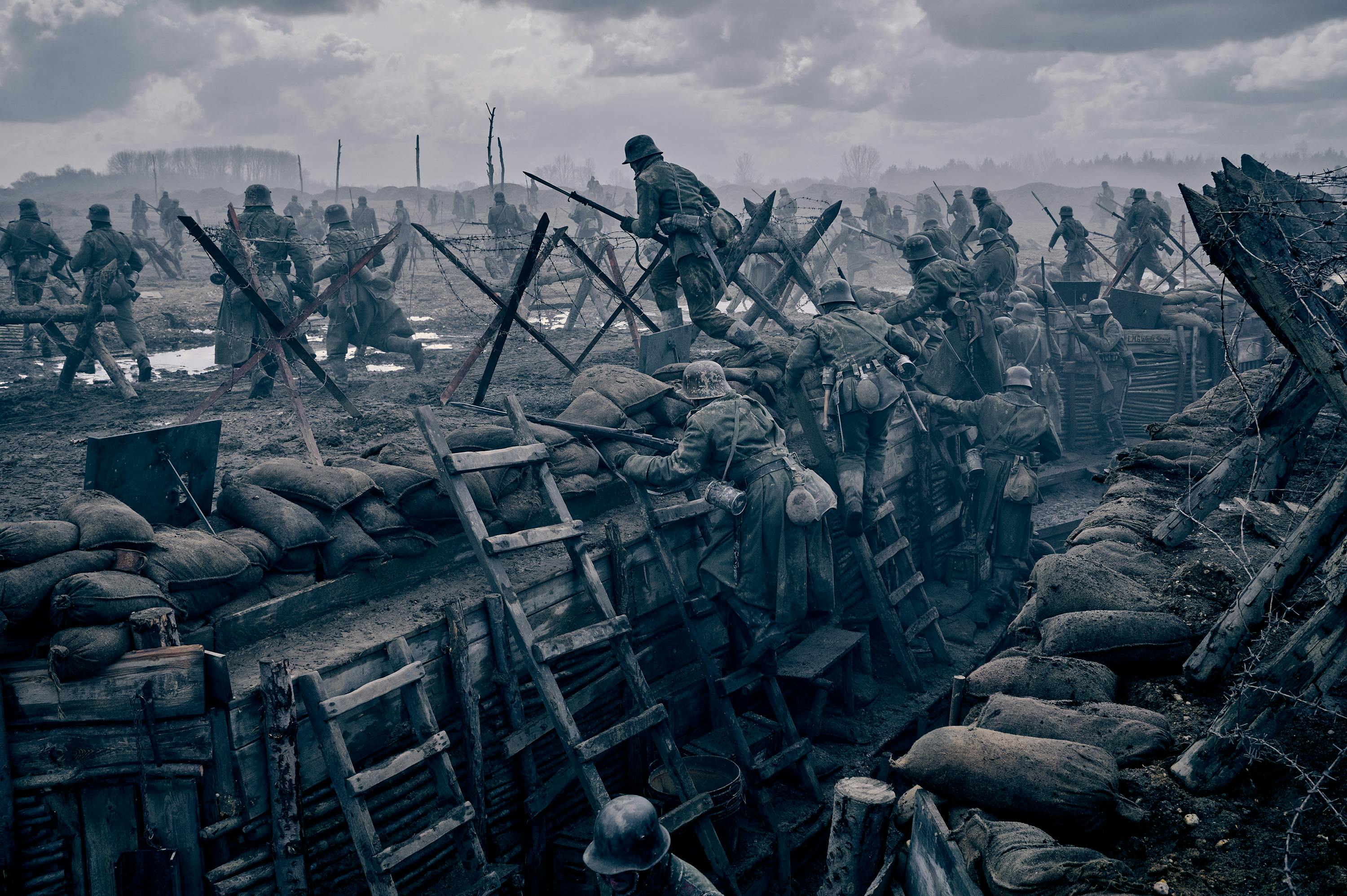 A grey battle scene in the trenches. Men in uniforms with guns scatter.
