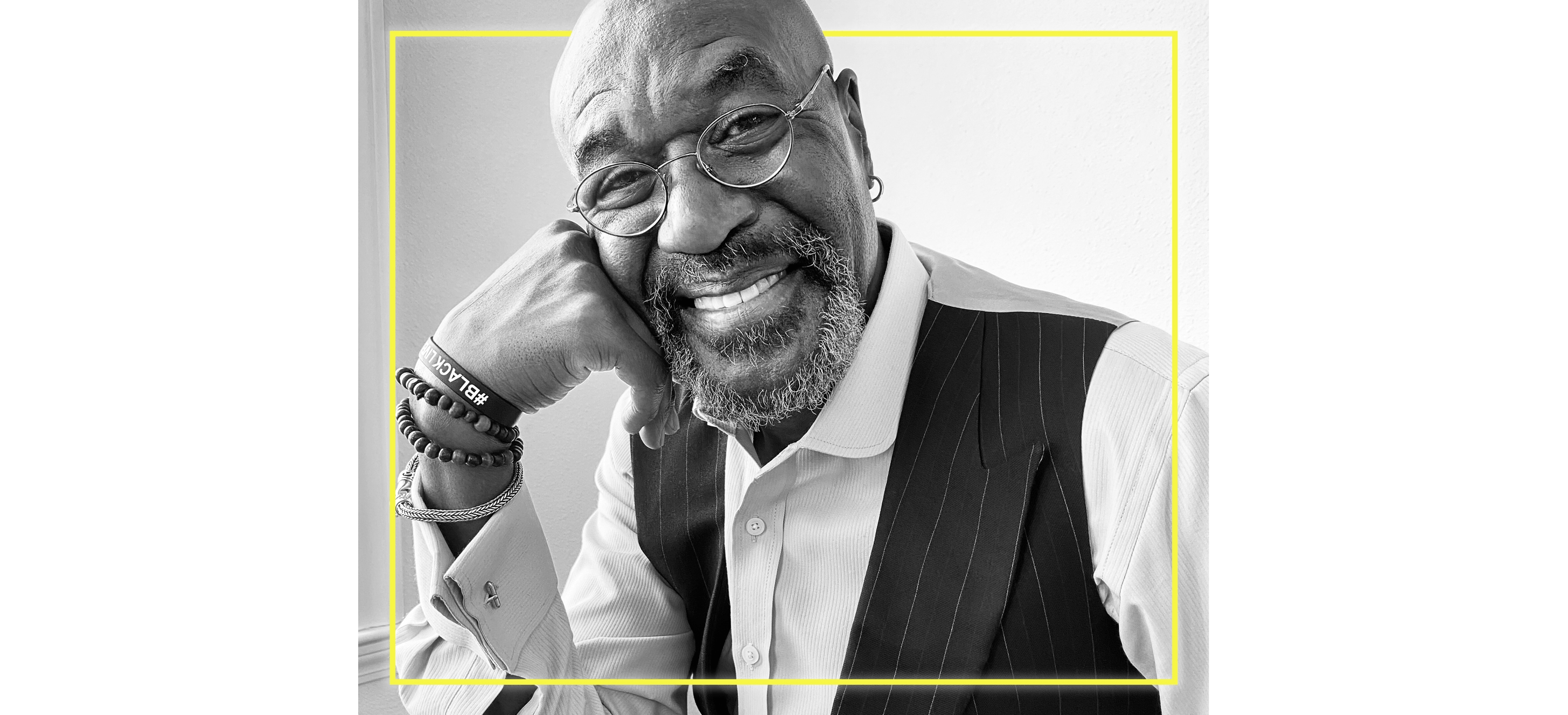 A black and white portrait of Delroy Lindo, smiling warmly at the camera.