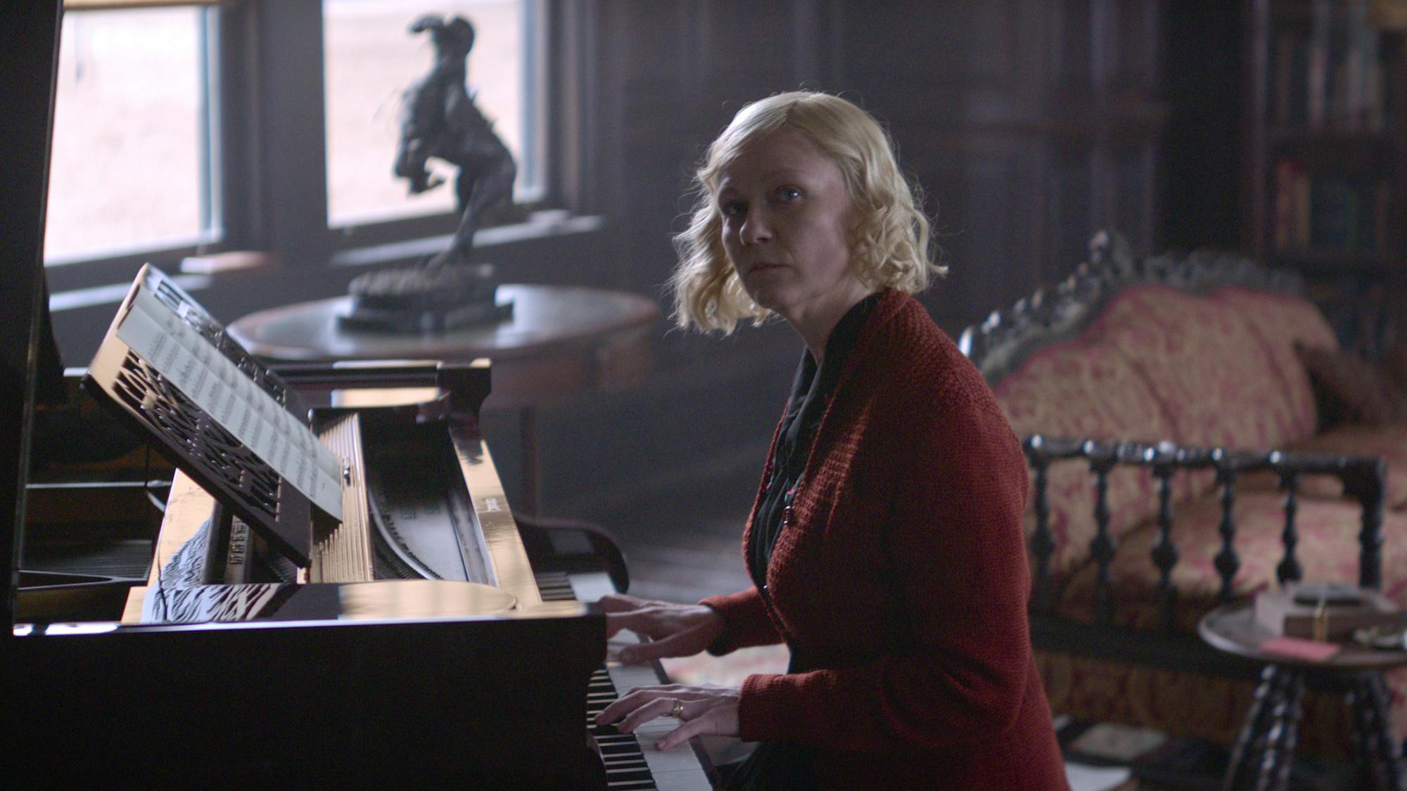 Kirsten Dunst as Rose sits at the piano in the scene where she is dueling musically with Benedict as Phil.