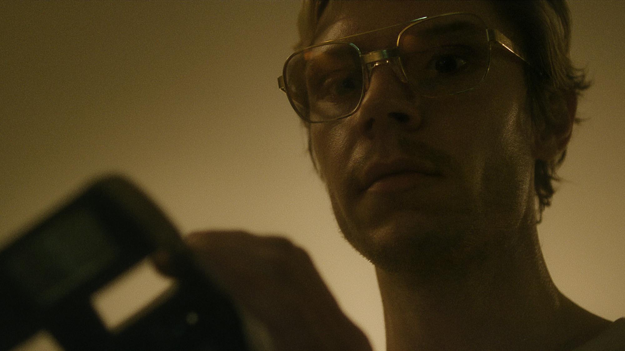 Jeffrey Dahmer (Evan Peters) holds something in this darkened photo.