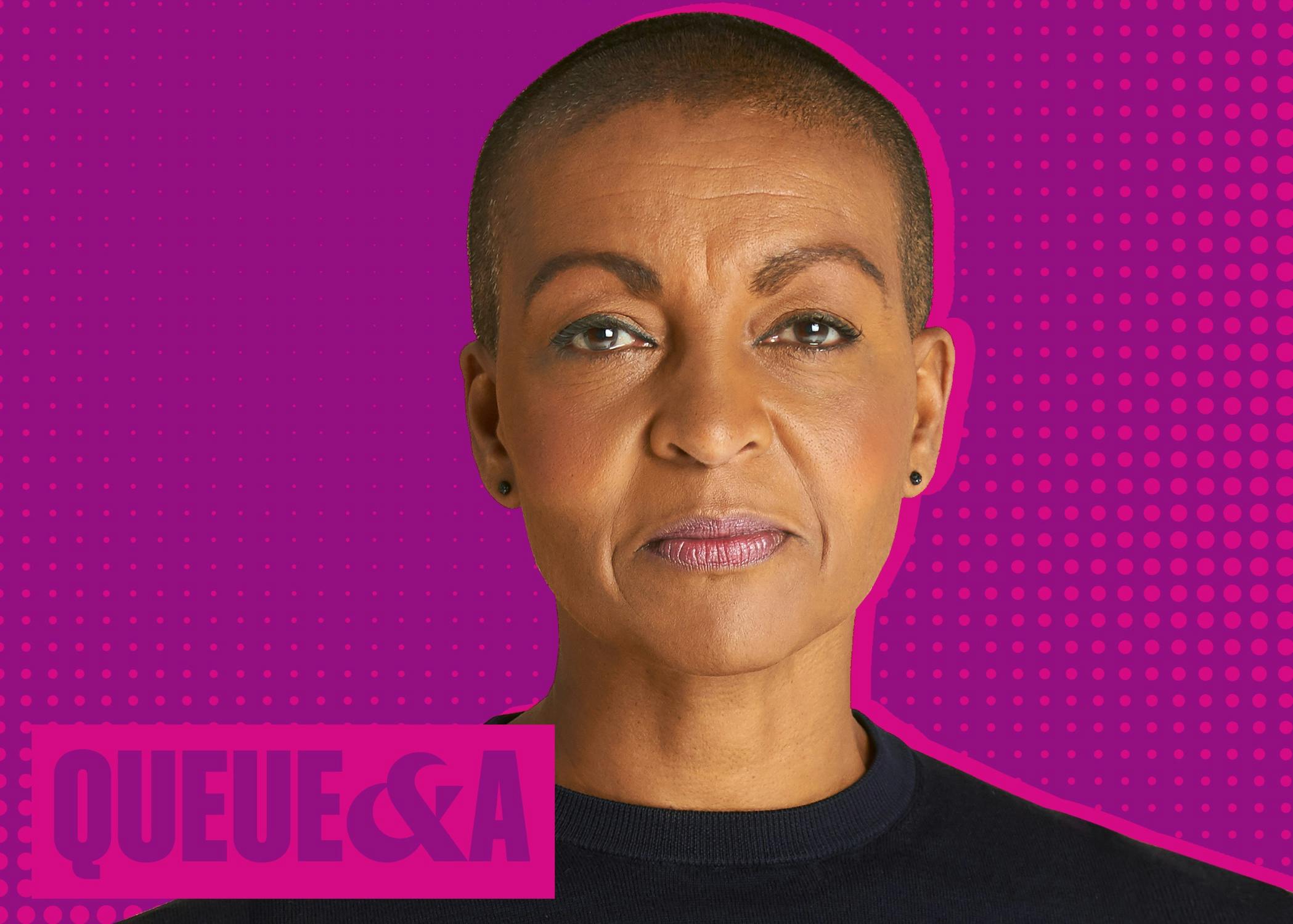 Adjoa Andoh smiles slightly in the warm toned portrait. She wears a black t-shirt, black earrings, and her head is shaved.