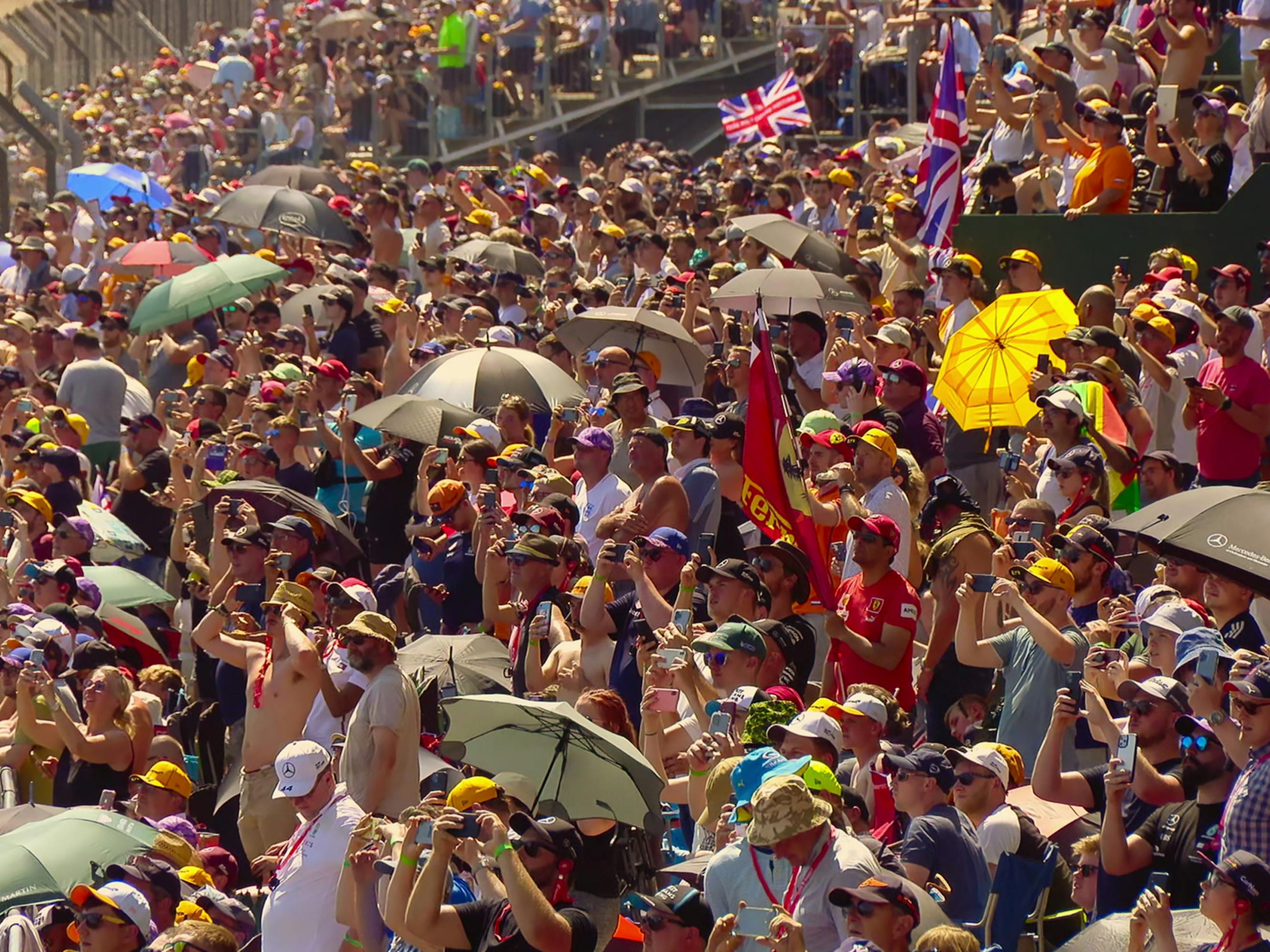 Formula 1 fans take videos and watch the race from the stands.