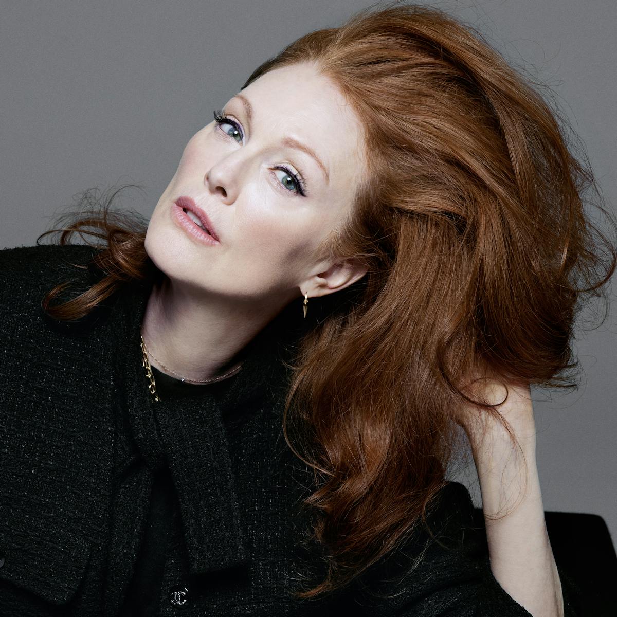 Julianne Moore wears a black ensemble and adjusts her red hair.