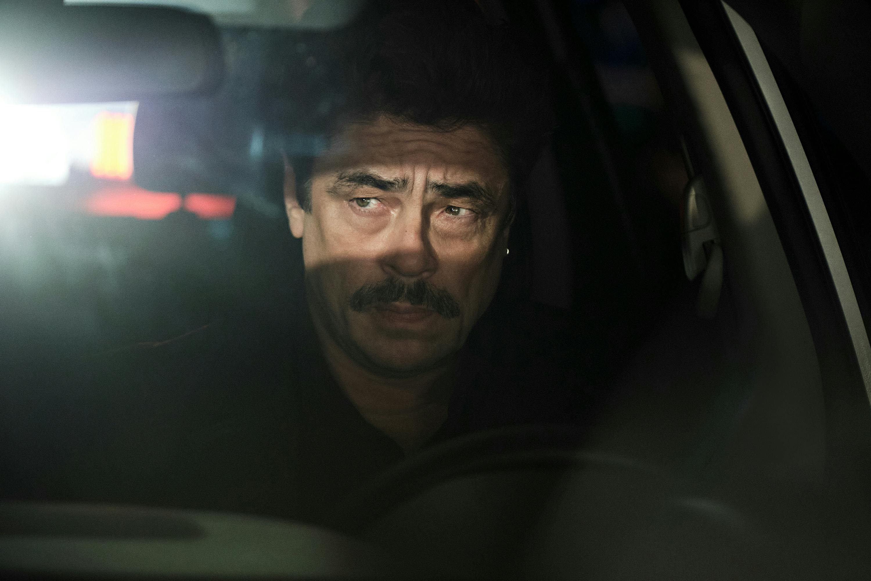 Tom Nichols (Benicio del Toro) frowns in a darkened car.