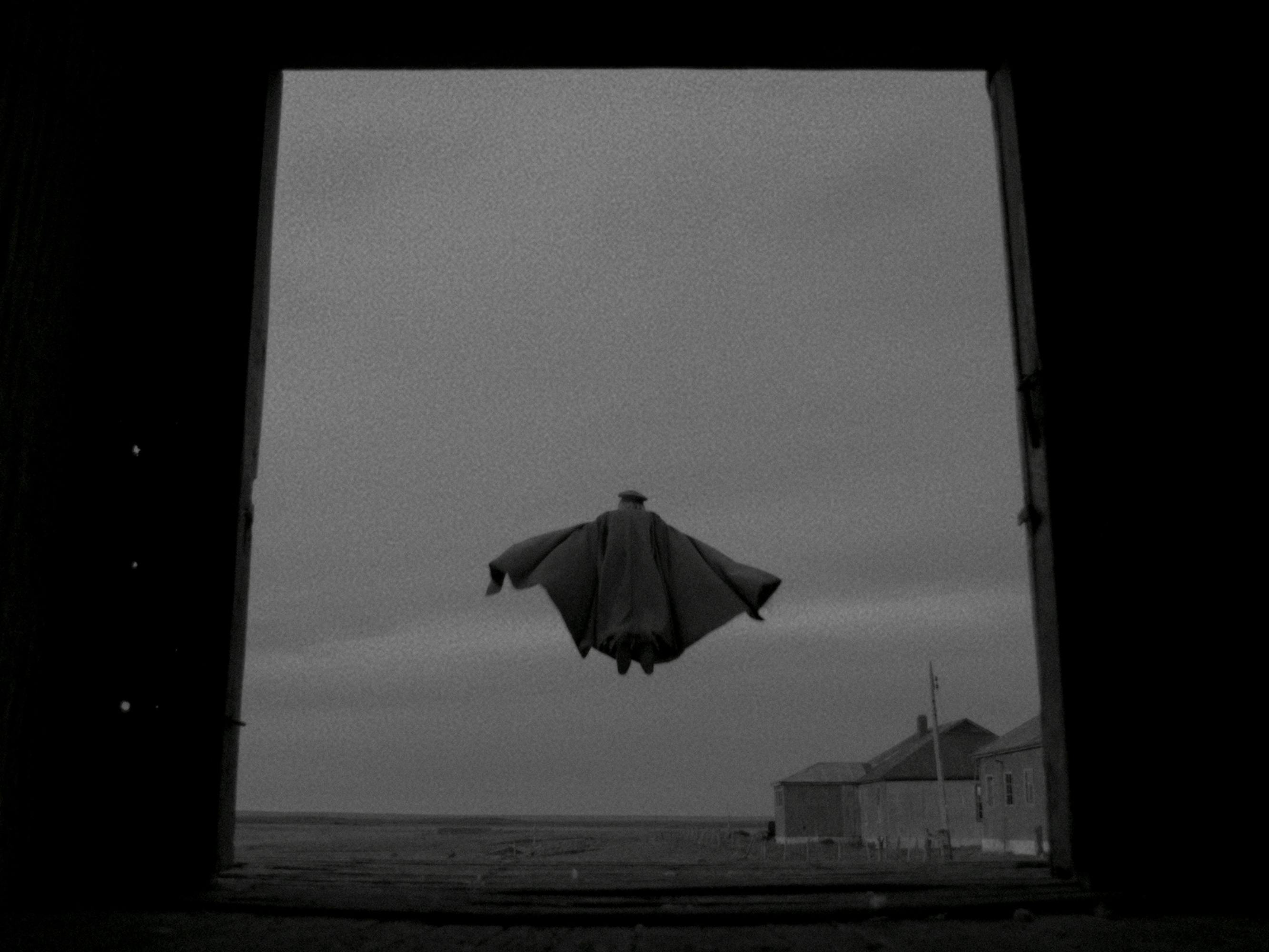 Augusto Pinochet (Jamie Vadell) wears a bat-like cape and flies into the gray sky.