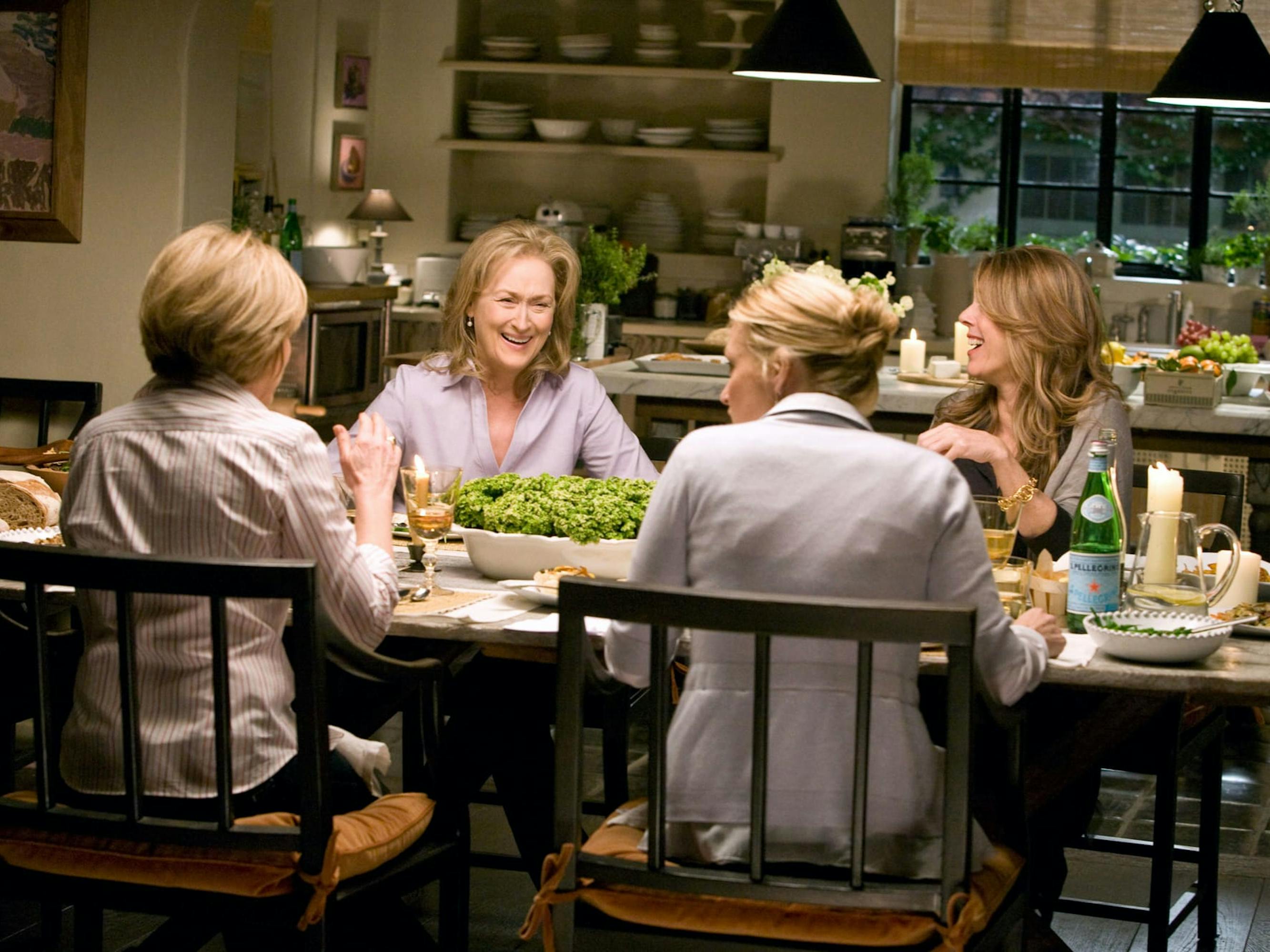Joanne (Mary Kay Place), Jane Adler (Meryl Streep), Trisha (Rita Wilson), and Diane (Alexandra Wentworth) in It’s Complicated sit around a dinner table laughing and talking.