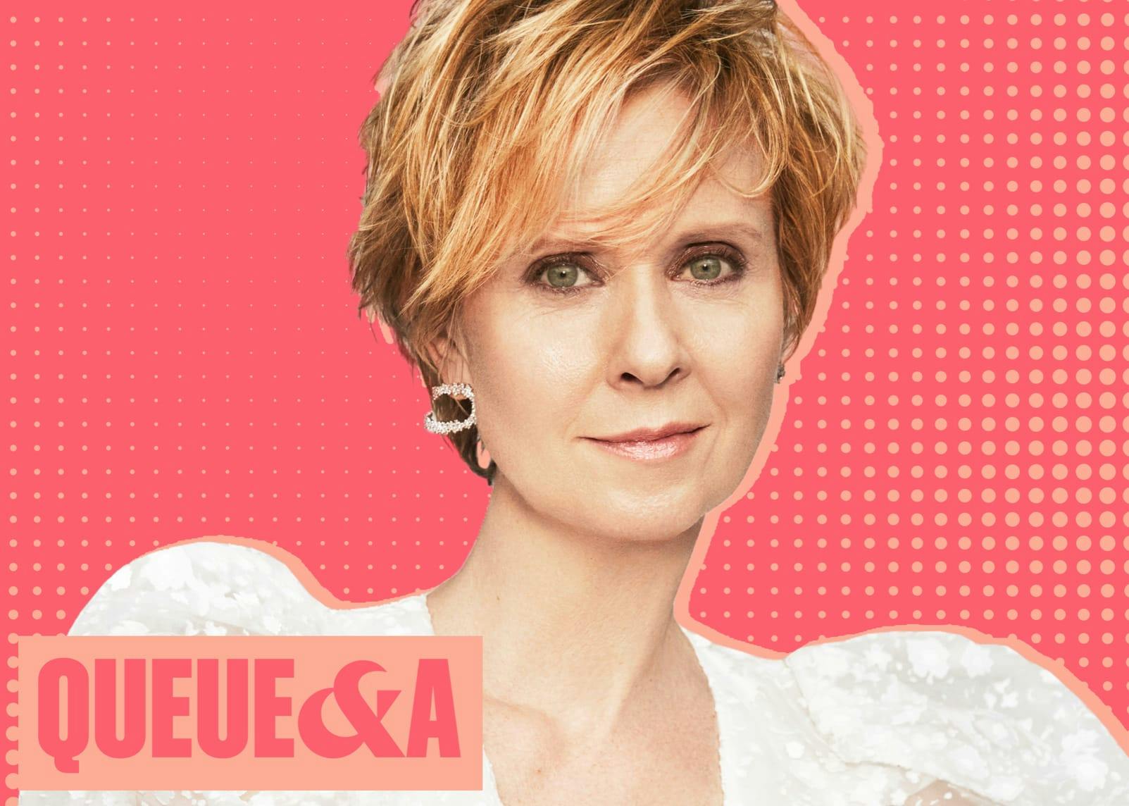 A portrait of Cynthia Nixon against a light pink and coral background. Nixon wears a white shirt, and silver earrings. In the bottom left hand corner reads ‘Queue & A.’