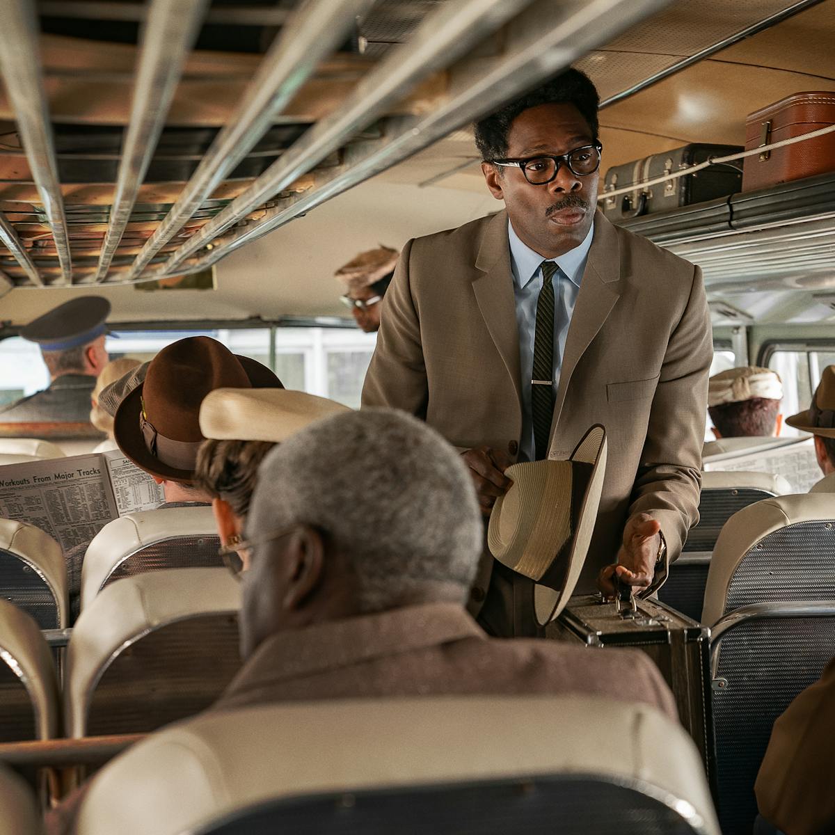 Bayard Rustin (Colman Domingo) walks through a bus wearing a beige jacket.
